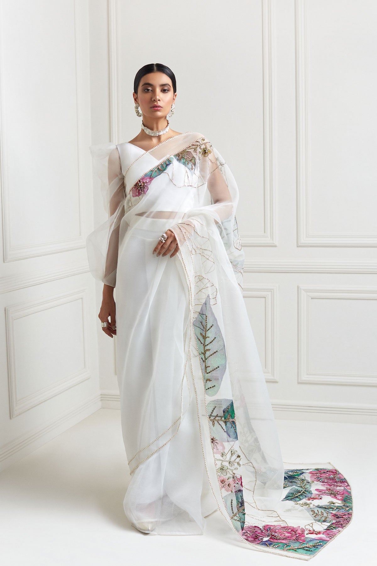 model in a front shot wearing hand-painted white organza floral saree paired with a draped one-sleeved organza blouse