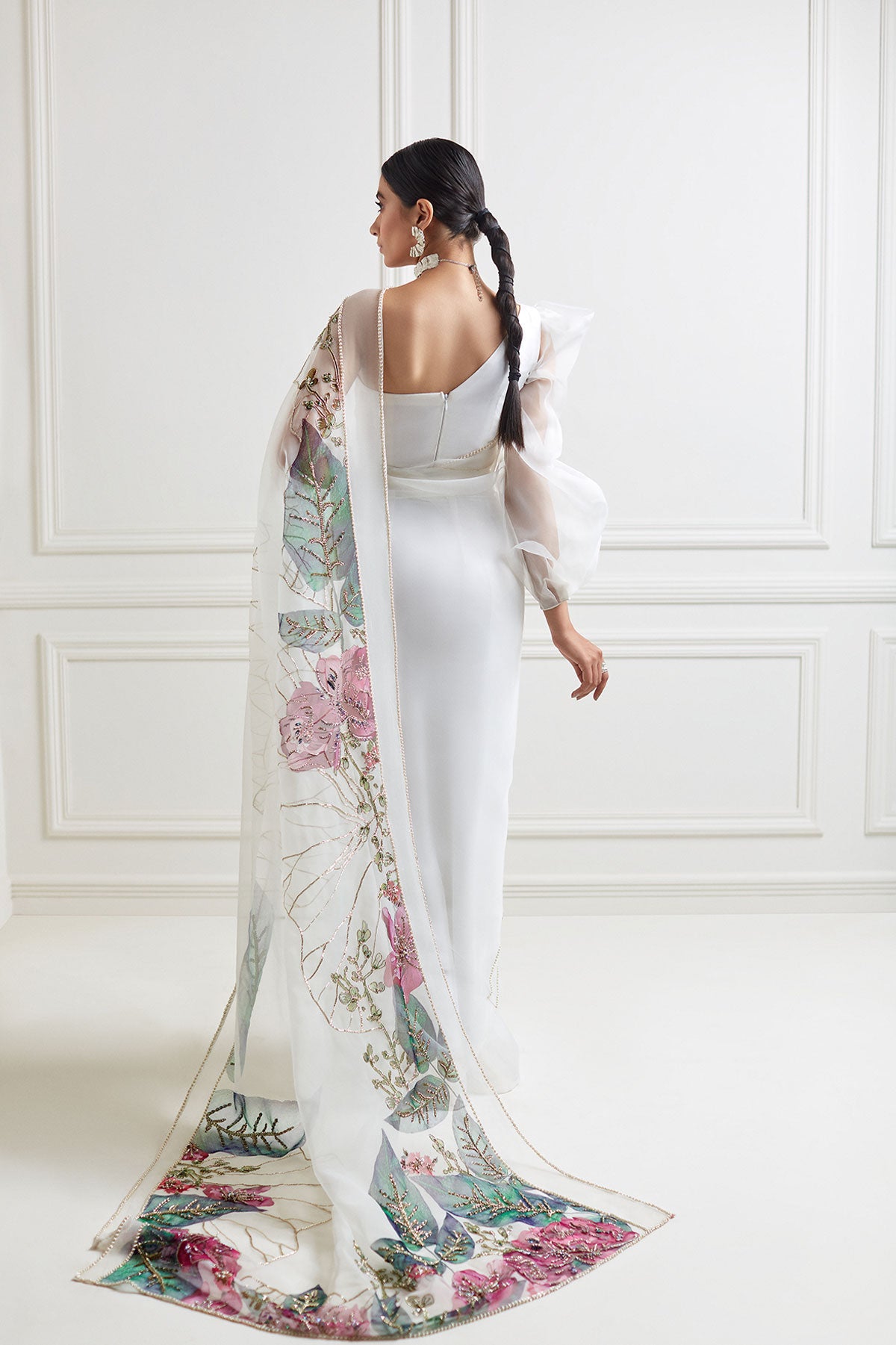 model in a back shot wearing hand-painted white organza floral saree paired with a draped one-sleeved organza blouse