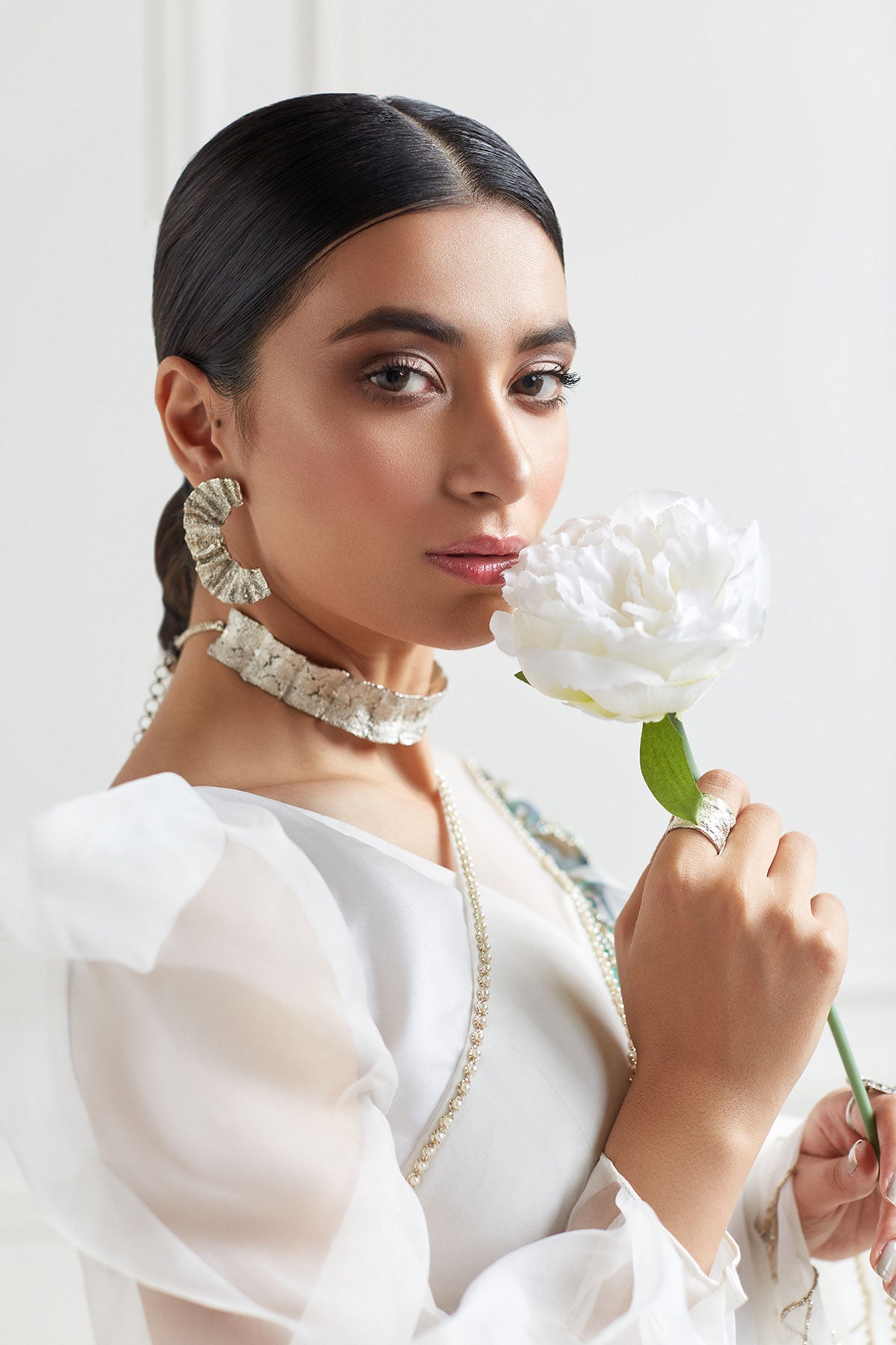 model in a front closeup shot wearing hand-painted white organza floral saree paired with a draped one-sleeved organza blouse
