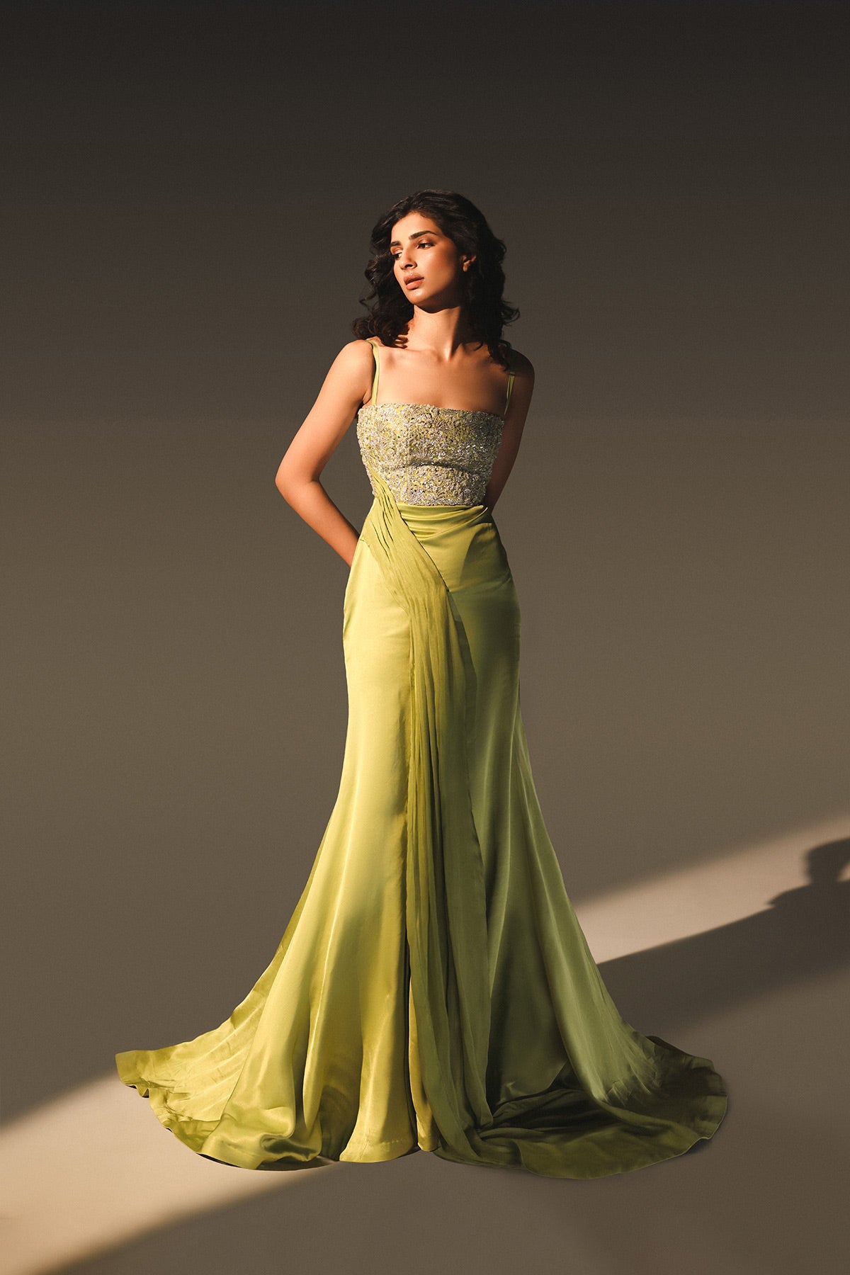 Woman wearing a green evening gown with a silver top against a gray background