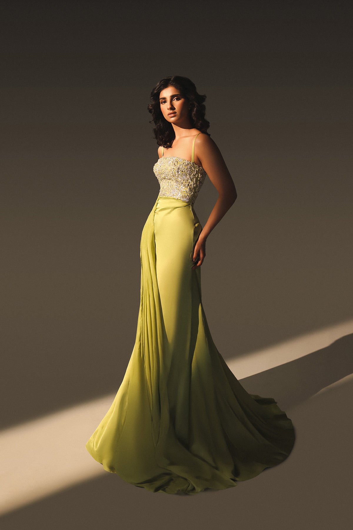 Woman in a strapless top and long green skirt against a neutral background