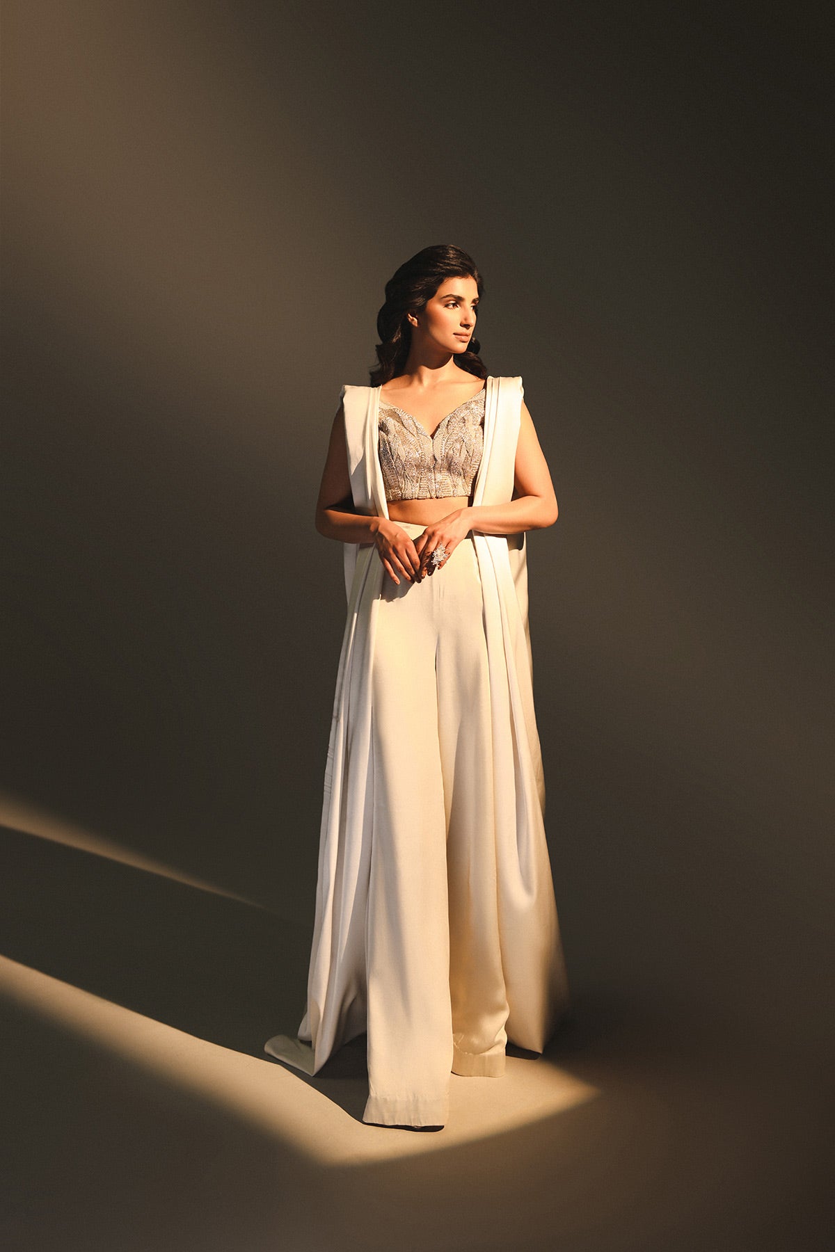 Woman in a white dress standing against a dark background