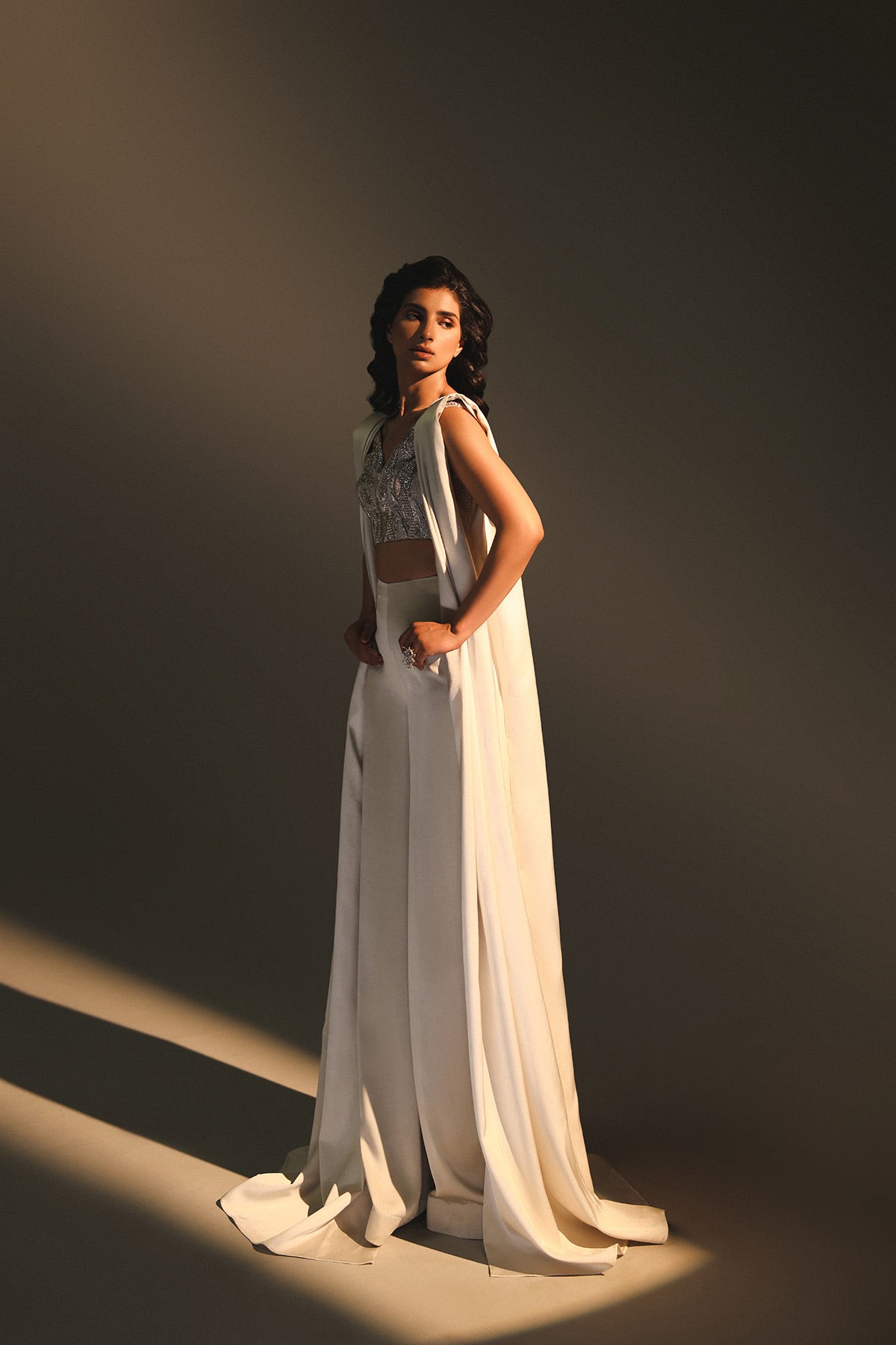Woman in a white dress standing against a dark background