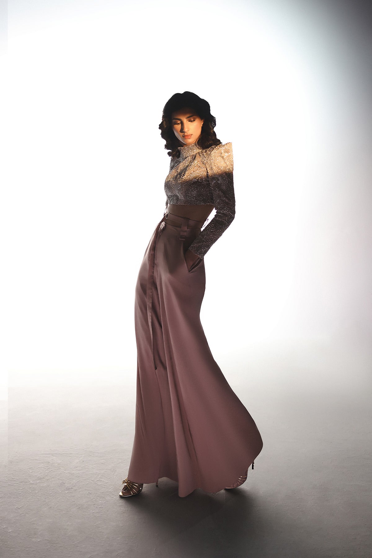 Woman wearing a long, elegant dress with a high collar against a white background