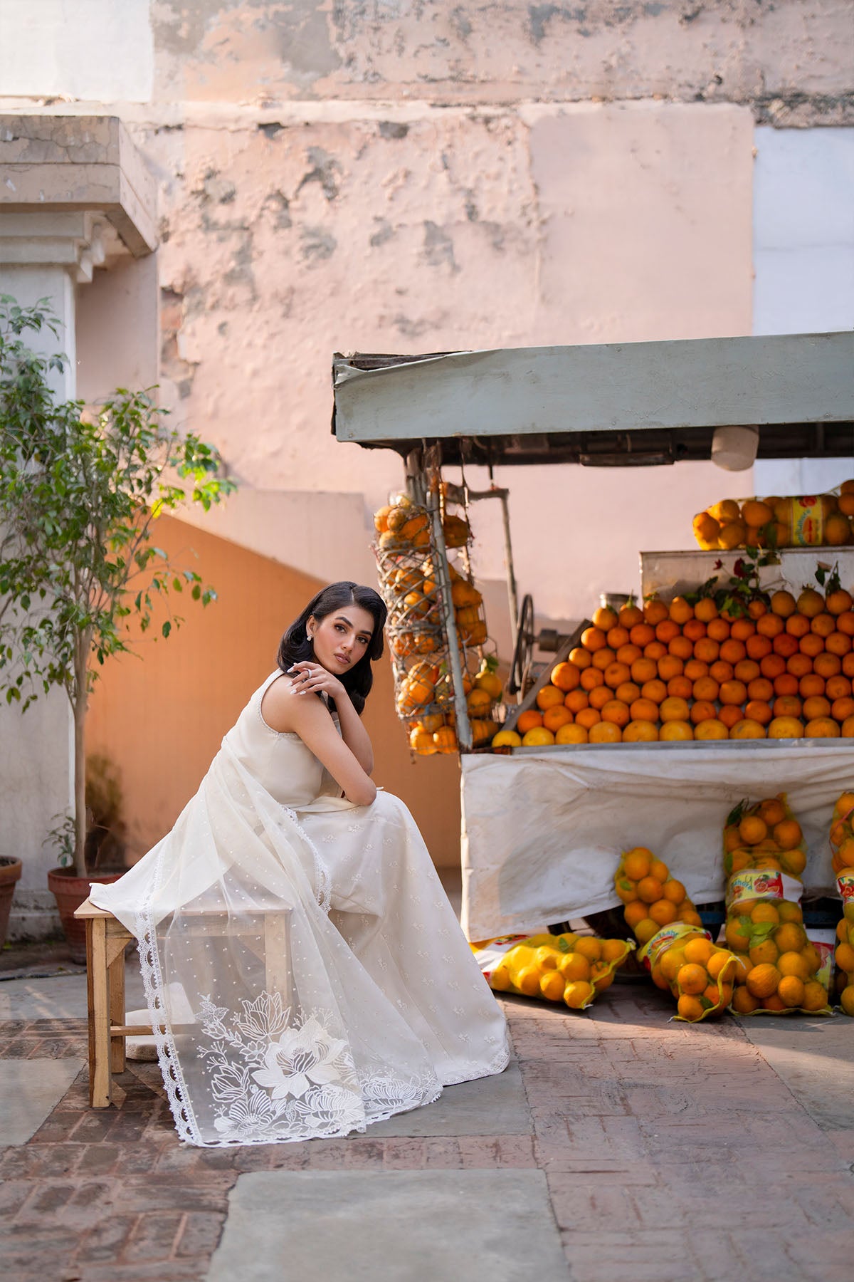 Model in a side shot wearing a beige silk shirt paired with screen-printed organza sharara pants.