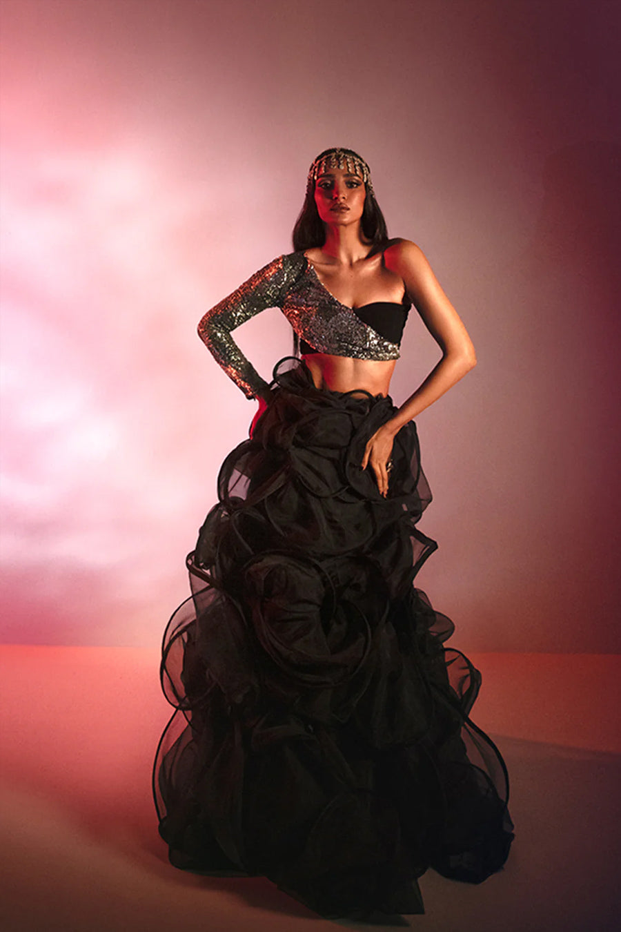 Model in a front shot wearing a black formal silk blouse with silver sequins and a sheer black back, paired with a fully ruffled black organza skirt