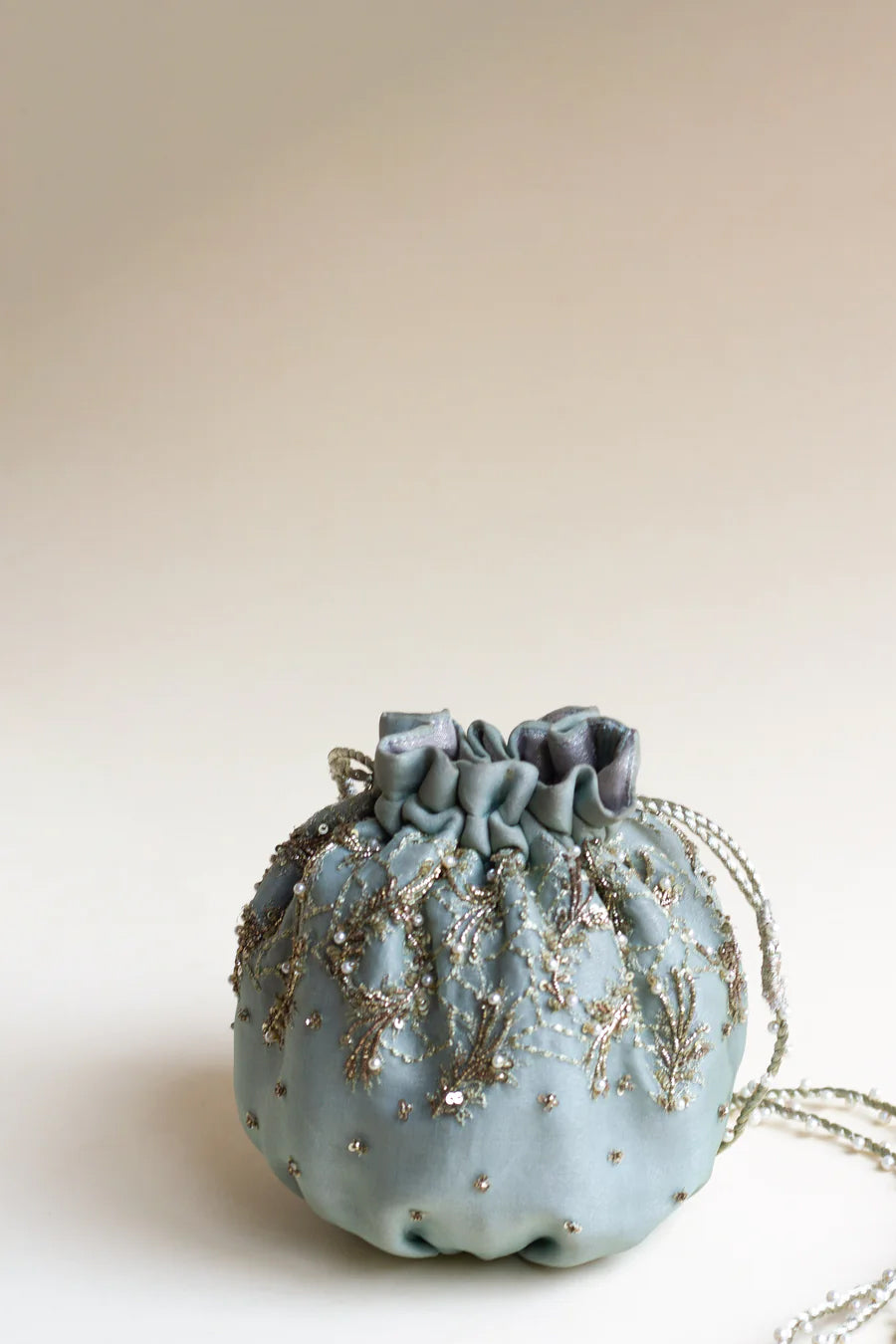 Full shot of blue organza silk pumpkin shaped pouch paired with pearl dori