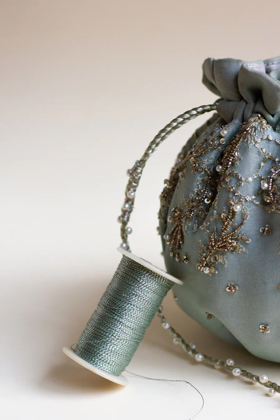 Half shot of blue organza silk pumpkin shaped pouch paired with pearl dori