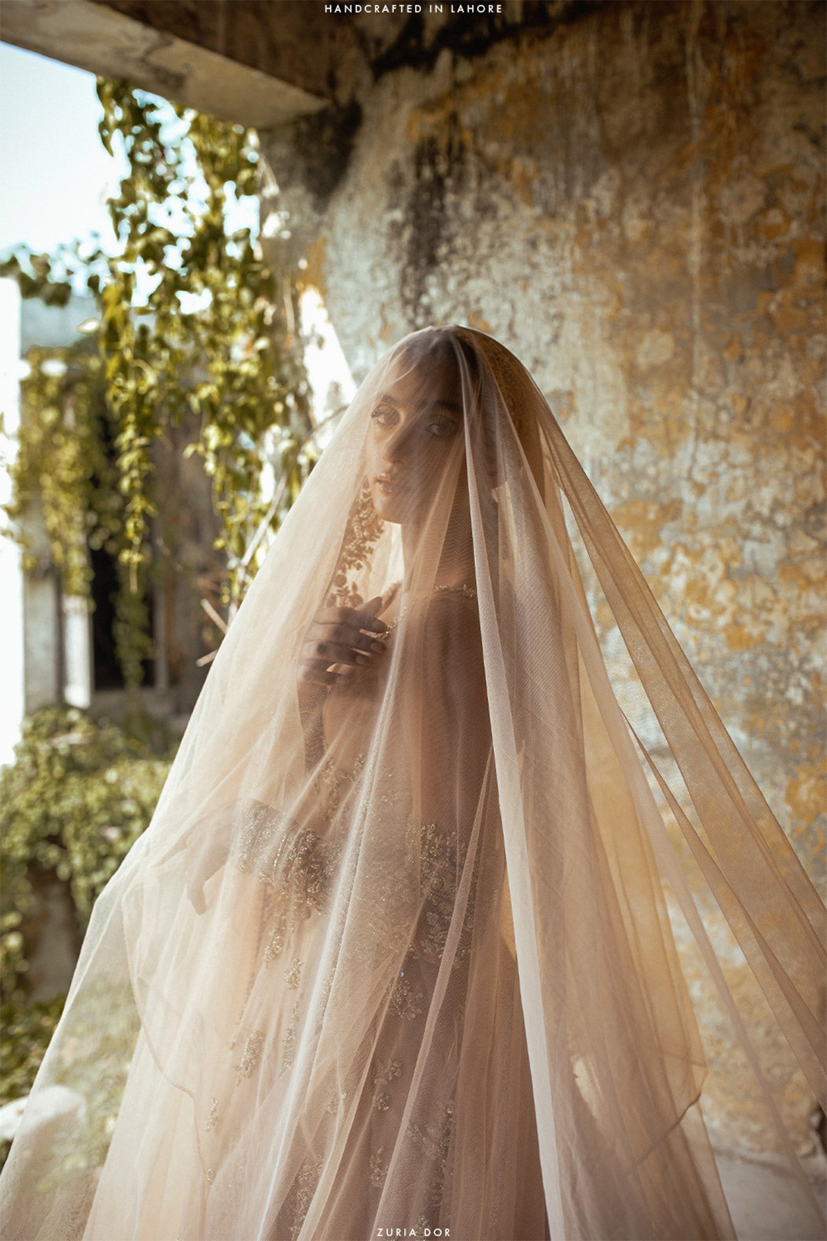 Rabia Butt in a side closeup shot wearing blush pink silk organza choli accompanied by a net dupatta and net veil 