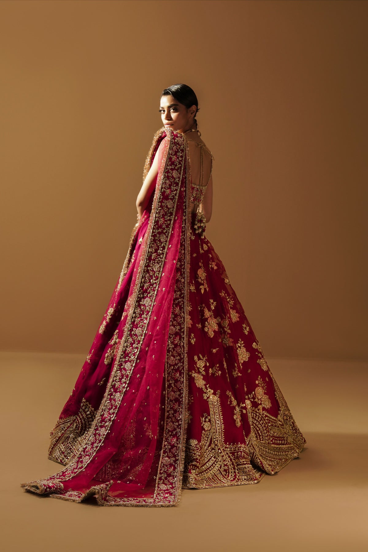 Model in a front view angle wearing a dark pink lehenga choli with handcrafted zardozi and sequin work and an organza dupatta