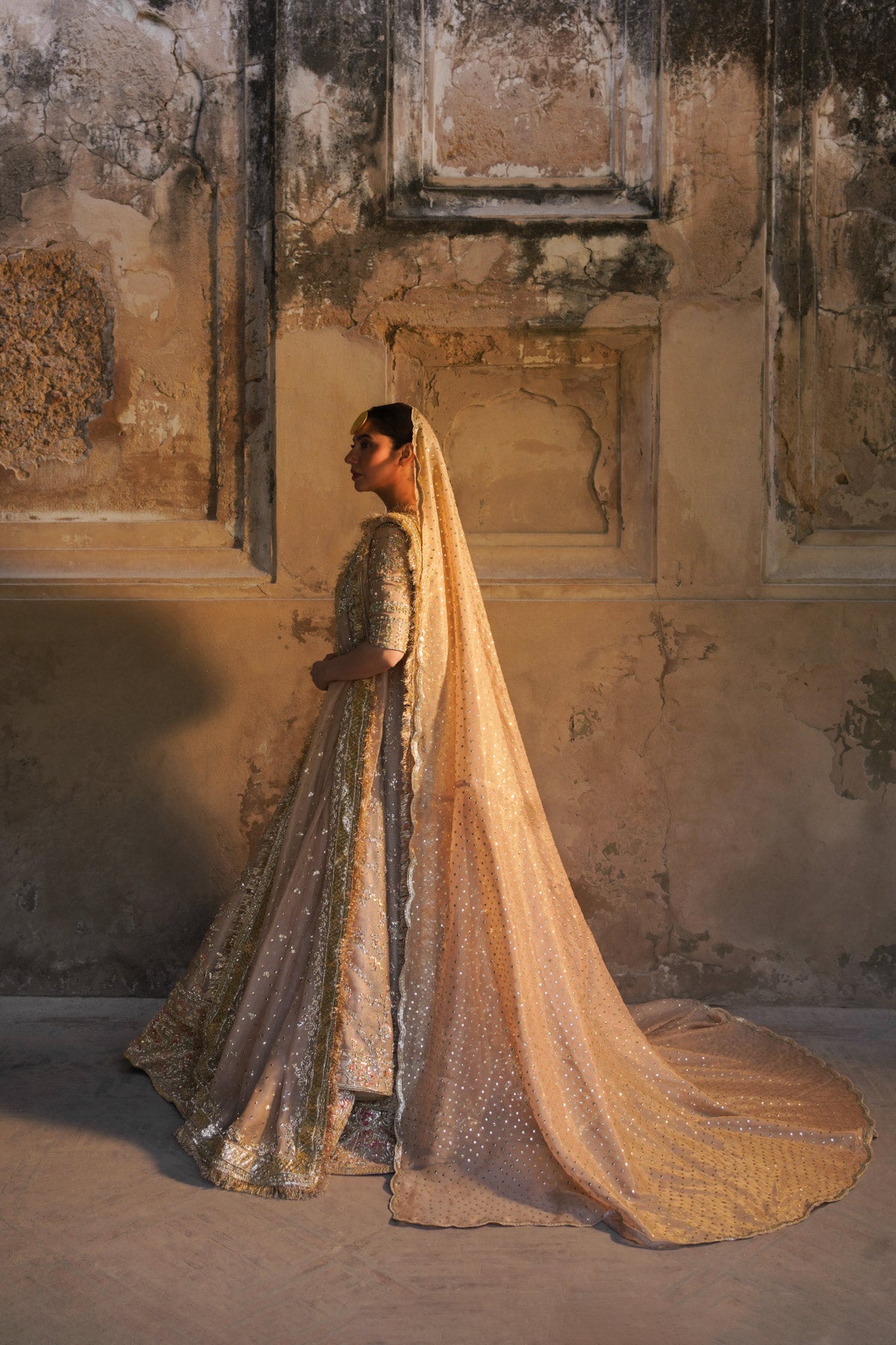 Mahira Khan in a side view angle wearing a dusty pink bridal peshwas by Zuria Dor paired with a handcrafted dupatta and an embellished lehenga