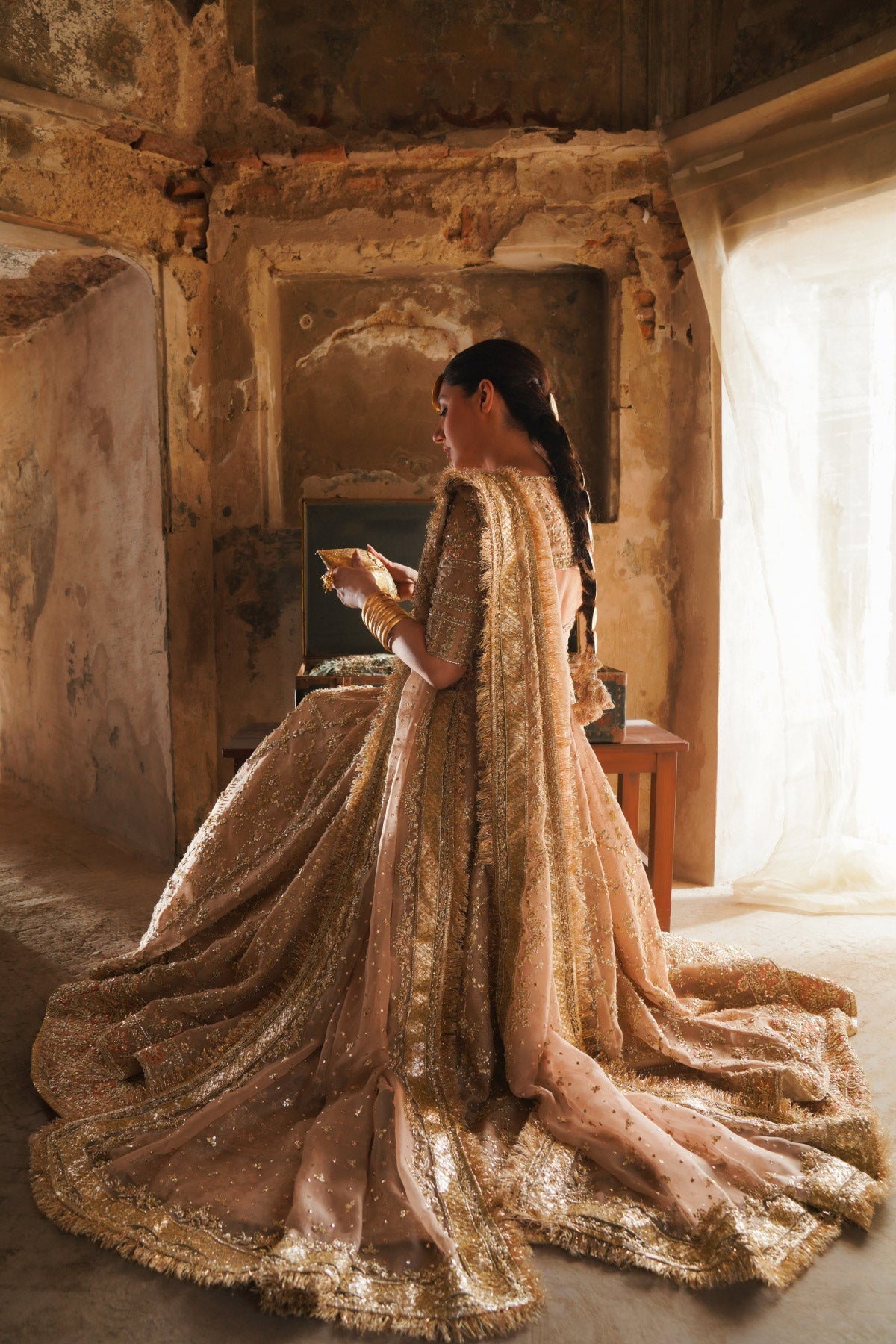 Mahira Khan in seated pose wearing a dusty pink bridal peshwas by zuria dor with paired with a handcrafted dupatta and embellished lehenga