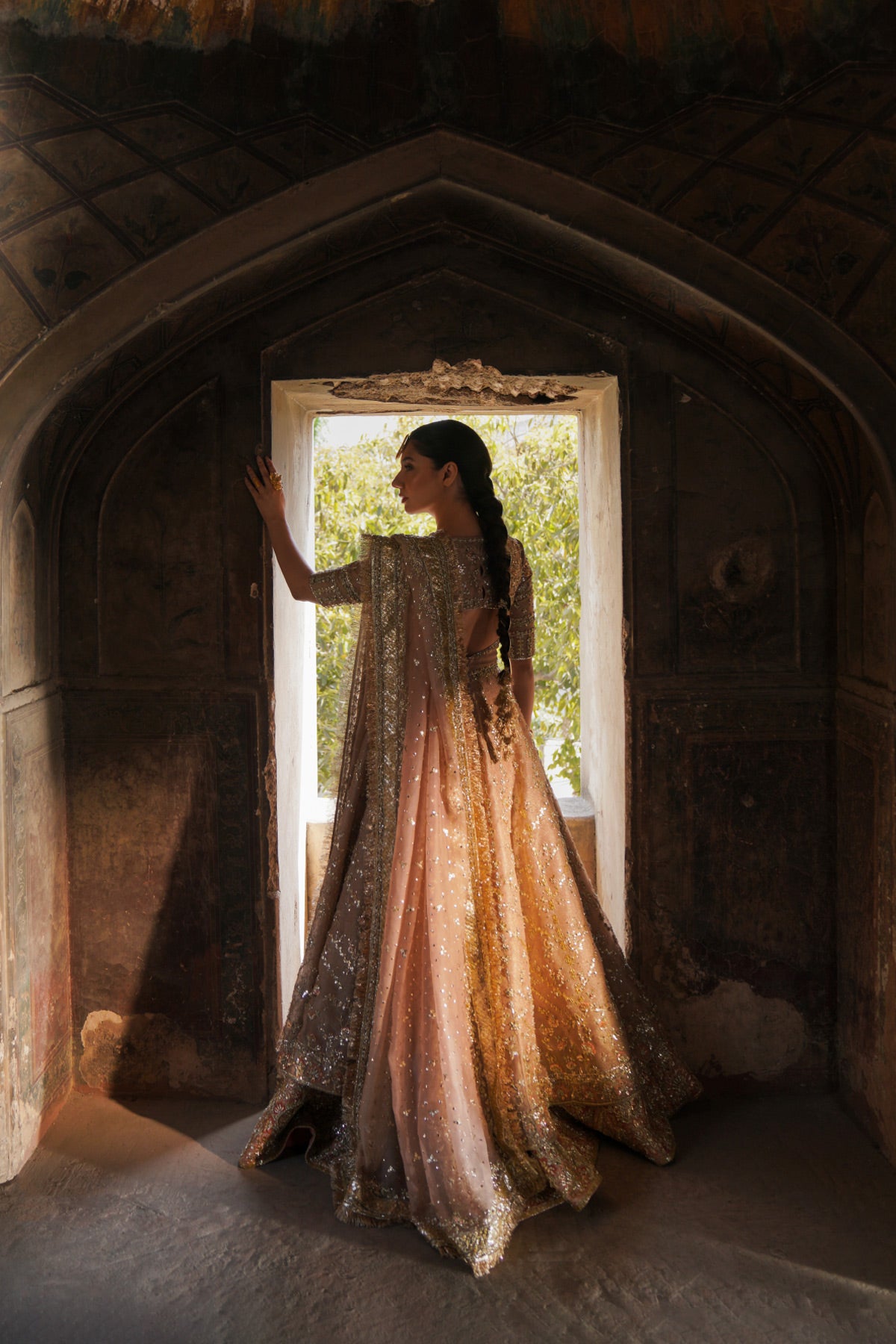 Mahira Khan in a back shot wearing a dusty pink bridal peshwas by Zuria Dor paired with a handcrafted dupatta and an embellished lehenga