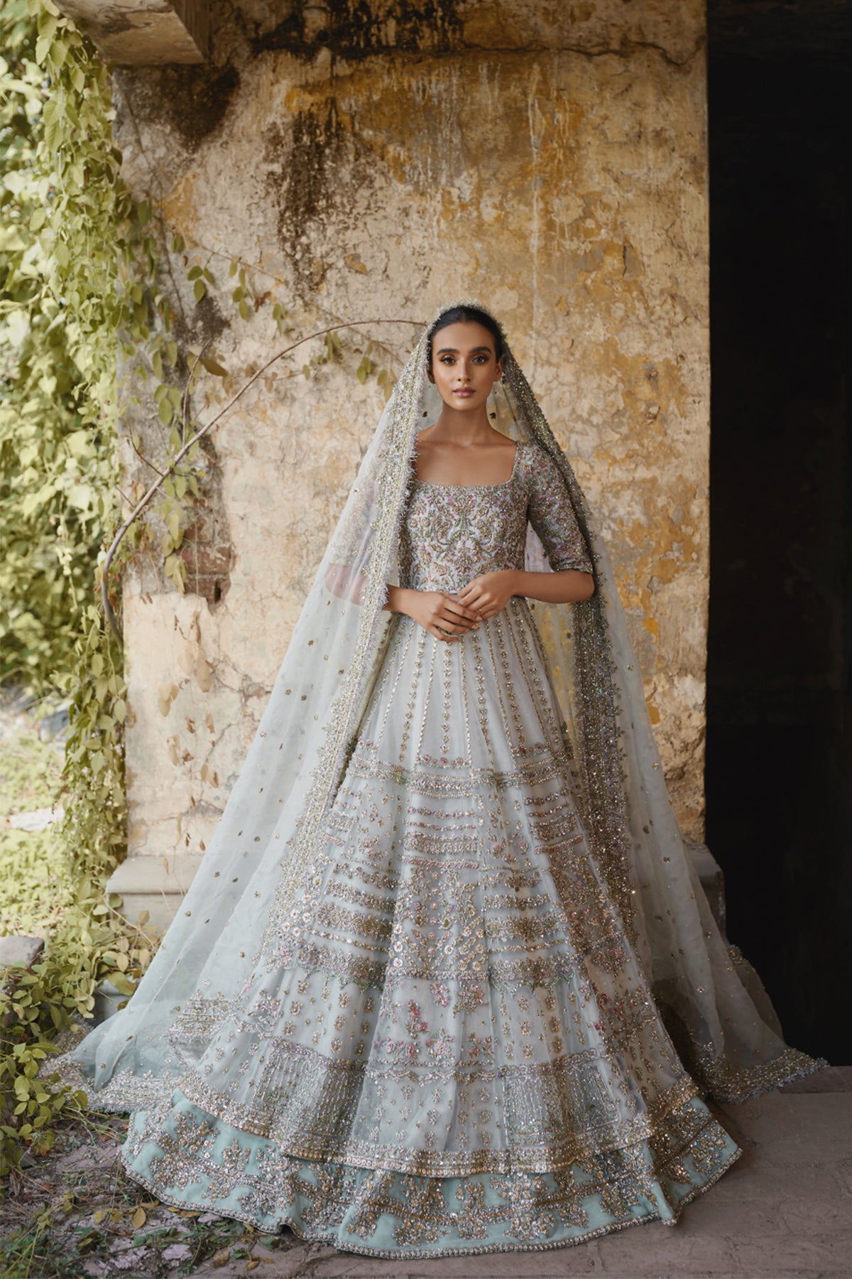 Model in a front shot wearing white net pishwas paired with a net lehenga and organza net dupatta