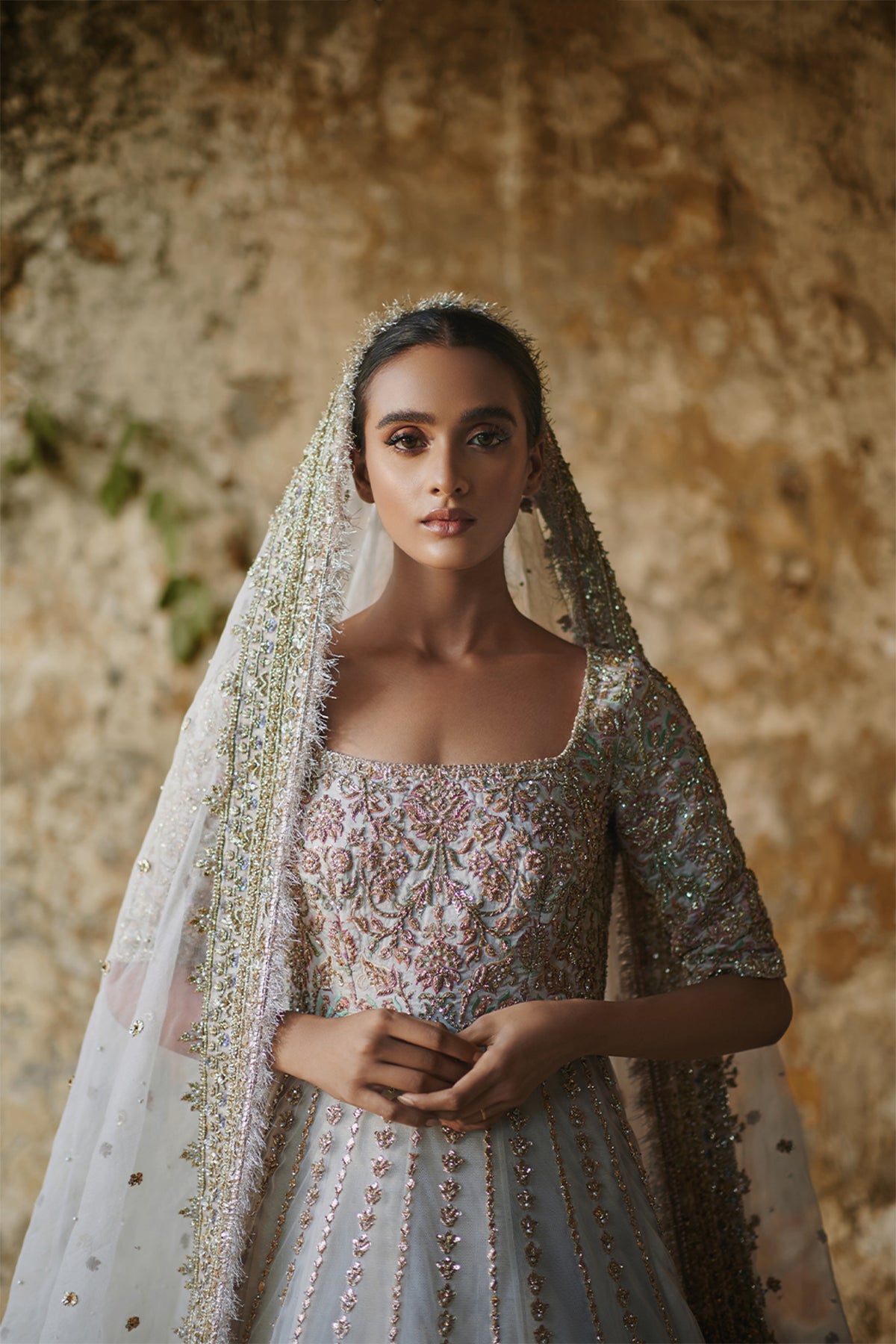 Model in a closeup front shot wearing white net pishwas paired with a net lehenga and organza net dupatta