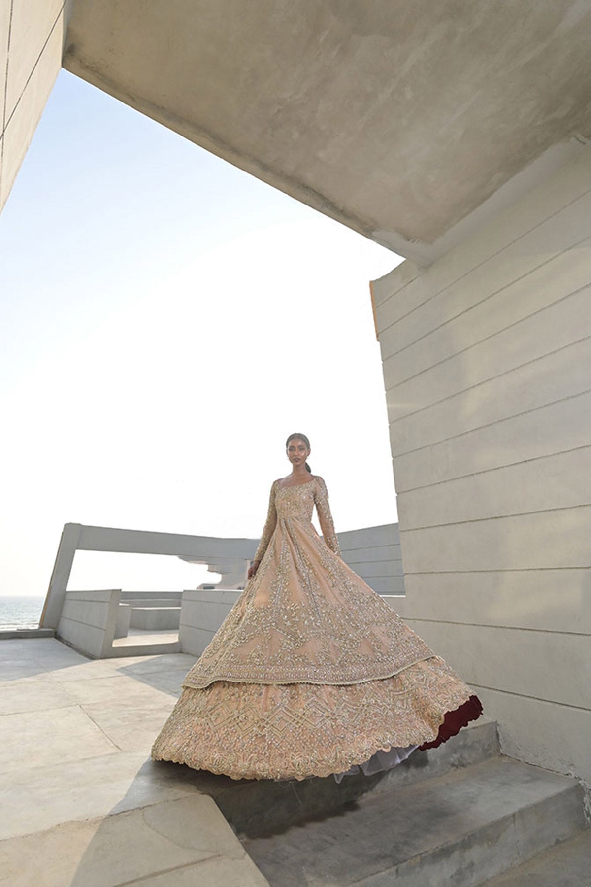 Model in a zoomed out shot wearing a dusty pink pishwas paired with lehenga 