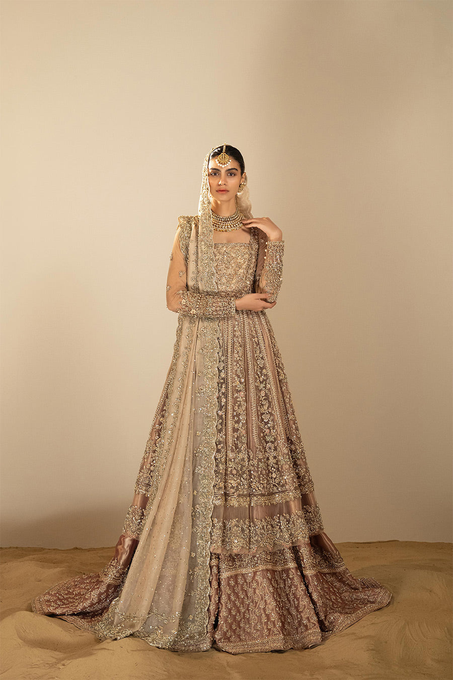 Model in a front shot wearing dusty pink net pishwas combined with a farshi sharara and a dusty pink silk organza dupatta 