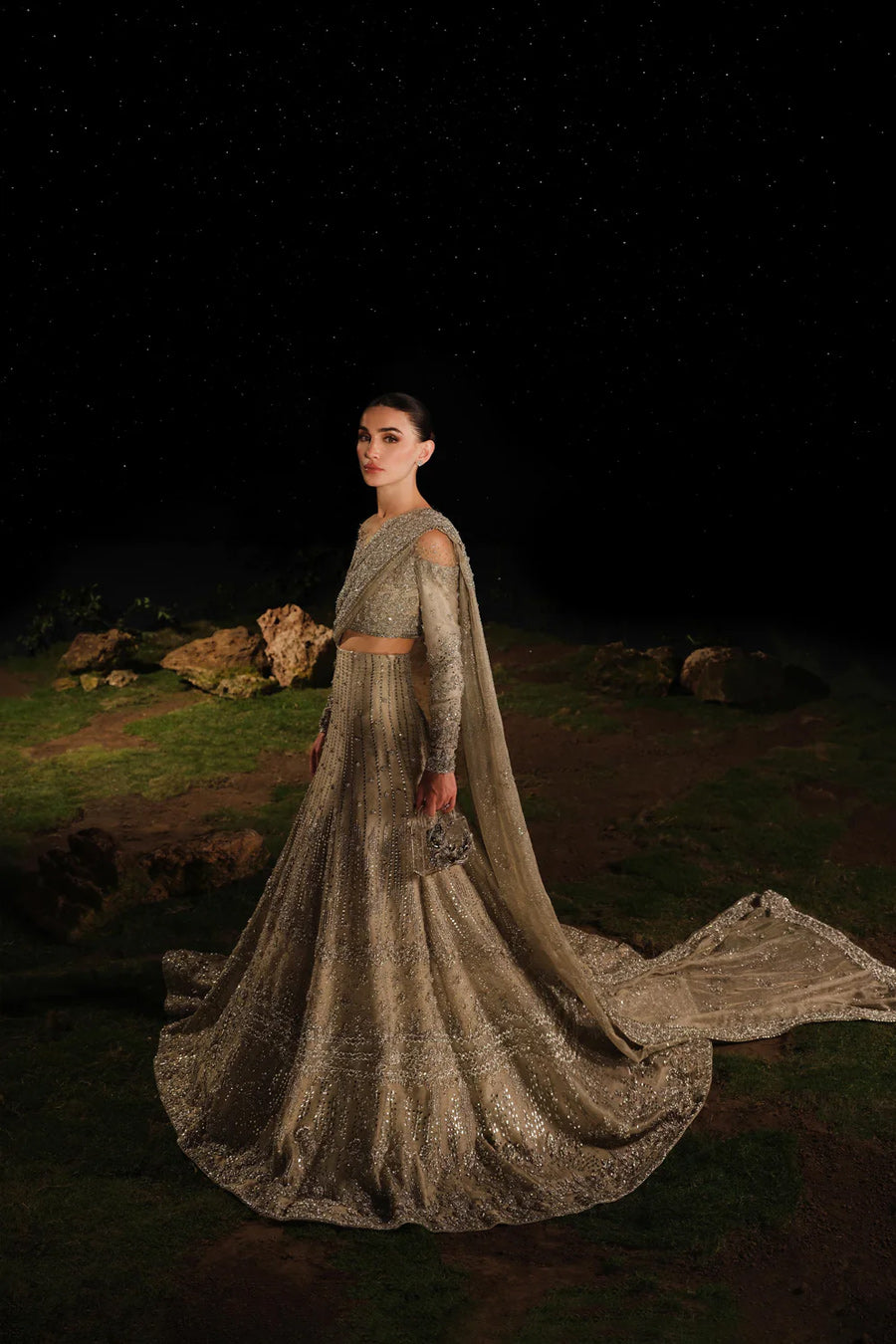 Model in front side shot wearing a gold and silver bridal lehenga with a train and an attached drape