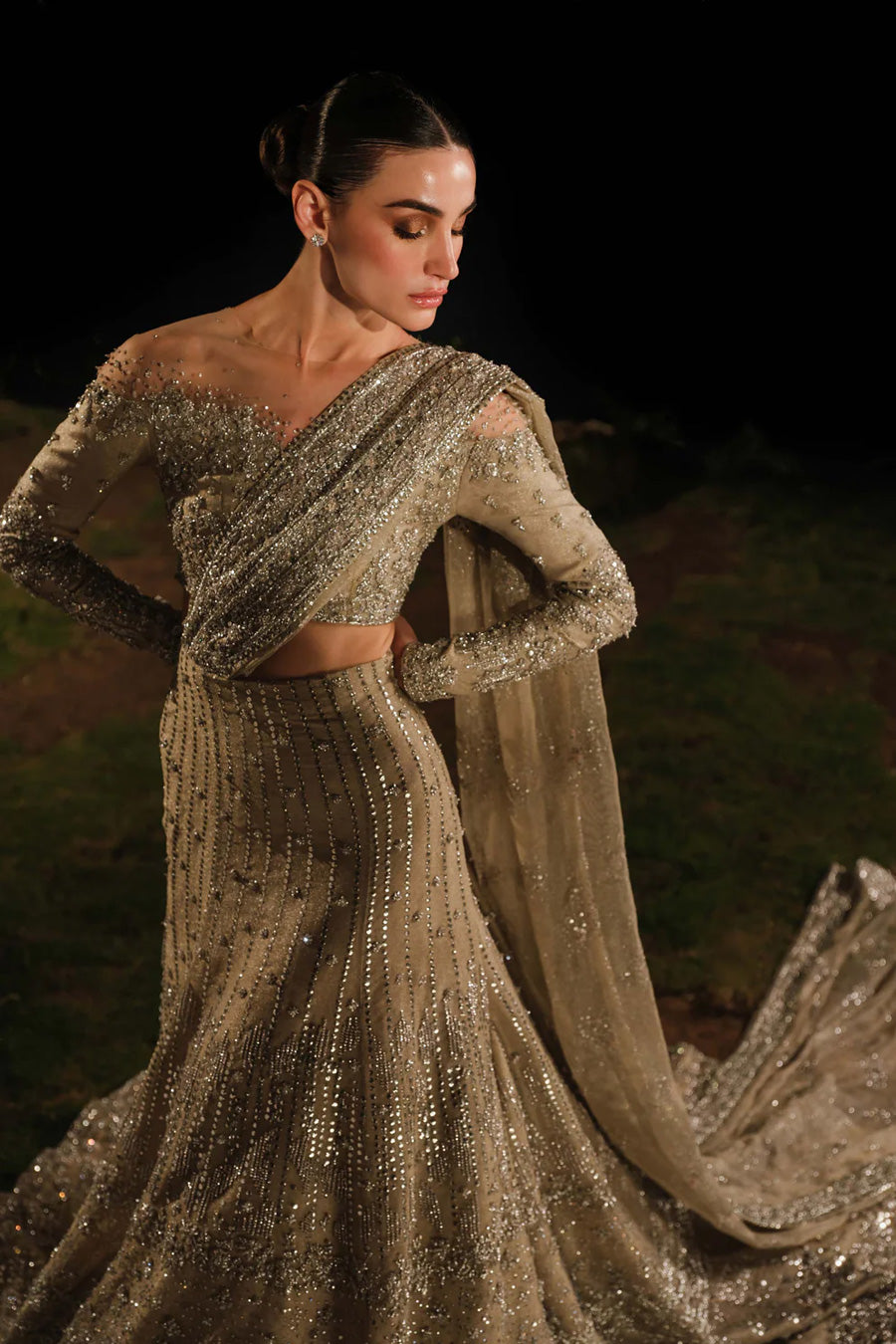 Model in top front side shot wearing a gold and silver bridal lehenga with a train and an attached drape