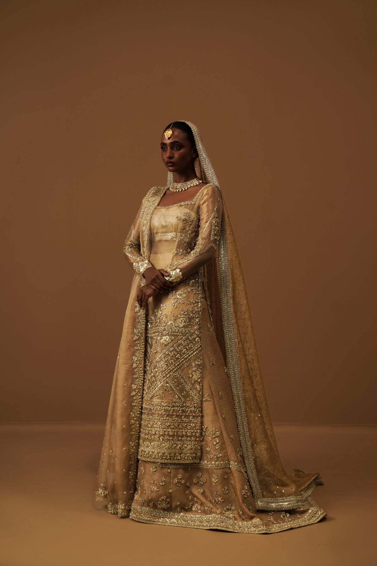 Model in a seated position wearing a golden tissue bridal shirt paired with a crushed tissue dupatta