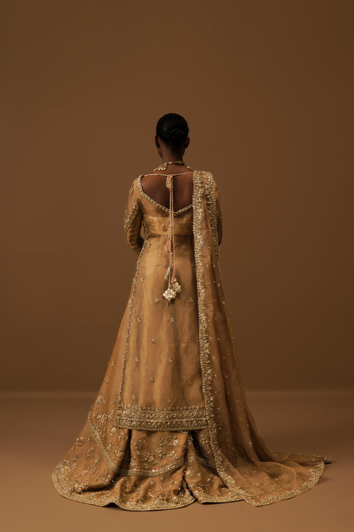 Model in a back shot wearing a golden tissue bridal shirt paired with a crushed tissue dupatta