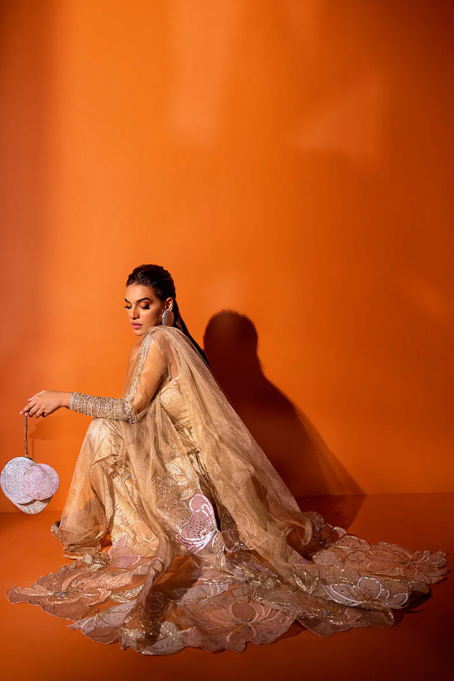 model in a seated shot wearing a golden formal kundan net dupatta paired a silk brocade bustier and wide-legged pants