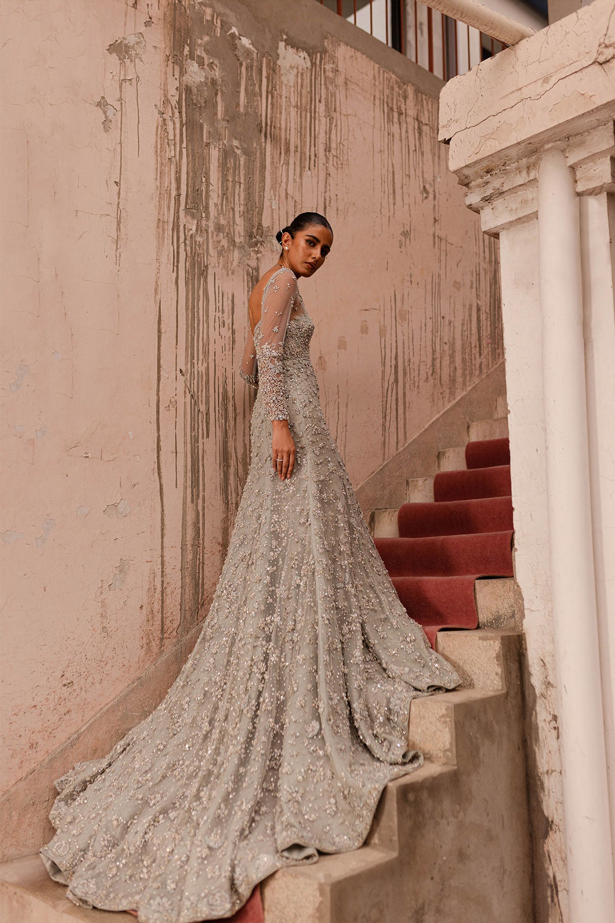 Model in a side shot wearing an ice-blue bridal gown with a floor length skirt with a train