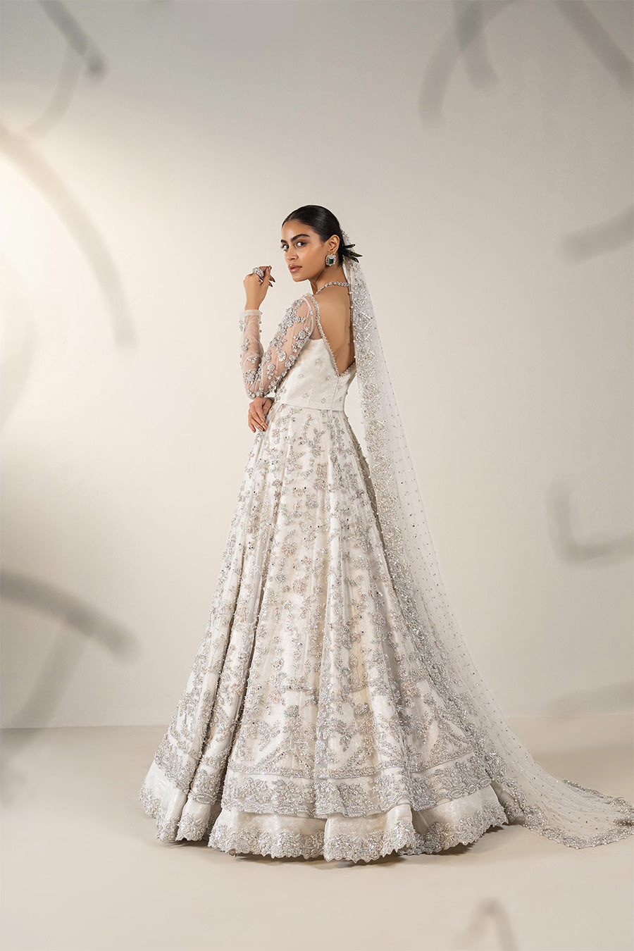 Model in a side shot wearing ivory bridal net pishwas paired with organza lehenga and a net veil