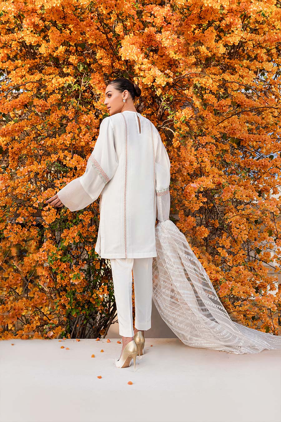 model in a back shot wearing a formal organza kurta paired with raw silk cigarette pants and printed organza dupatta