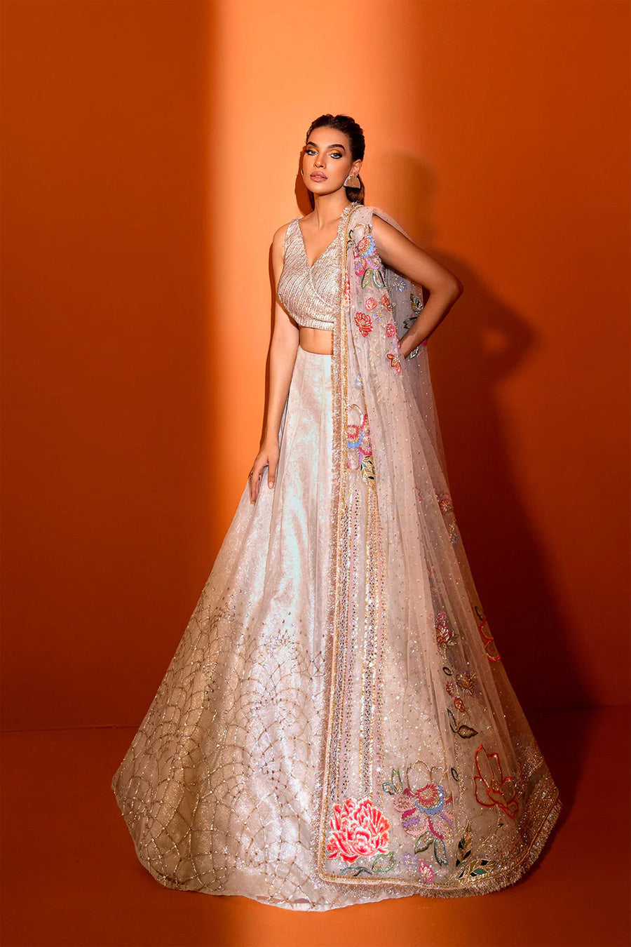 model in a front shot wearing ivory net dupatta paired with a hand-embellished organza lehenga and a silk brocade blouse