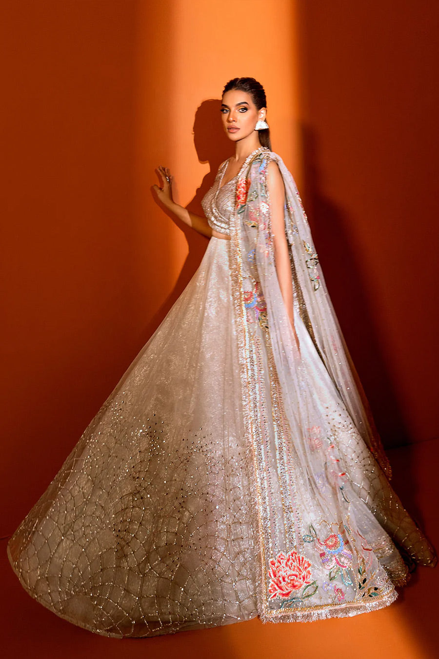 model in a side shot wearing ivory net dupatta paired with a hand-embellished organza lehenga and a silk brocade blouse