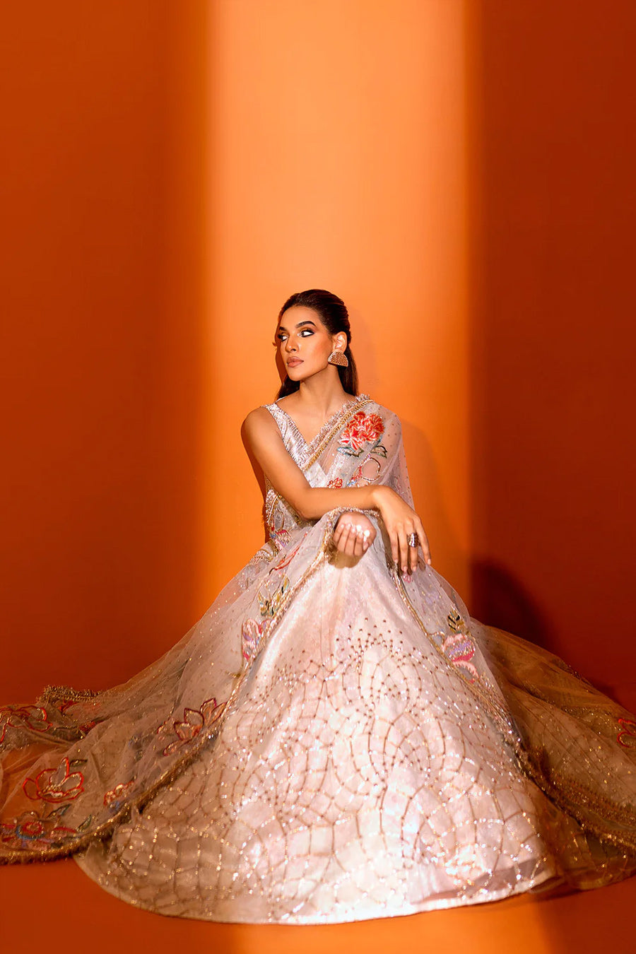 model in a seated shot wearing ivory net dupatta paired with a hand-embellished organza lehenga and a silk brocade blouse