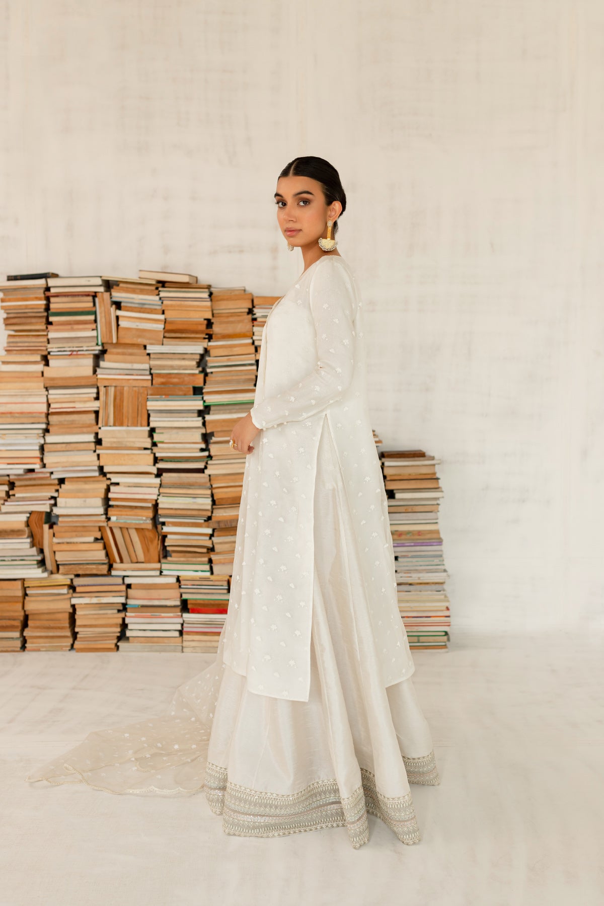 Model in a side view shot wearing an ivory organza shirt paired with an organza dupatta and a silk katan sharara