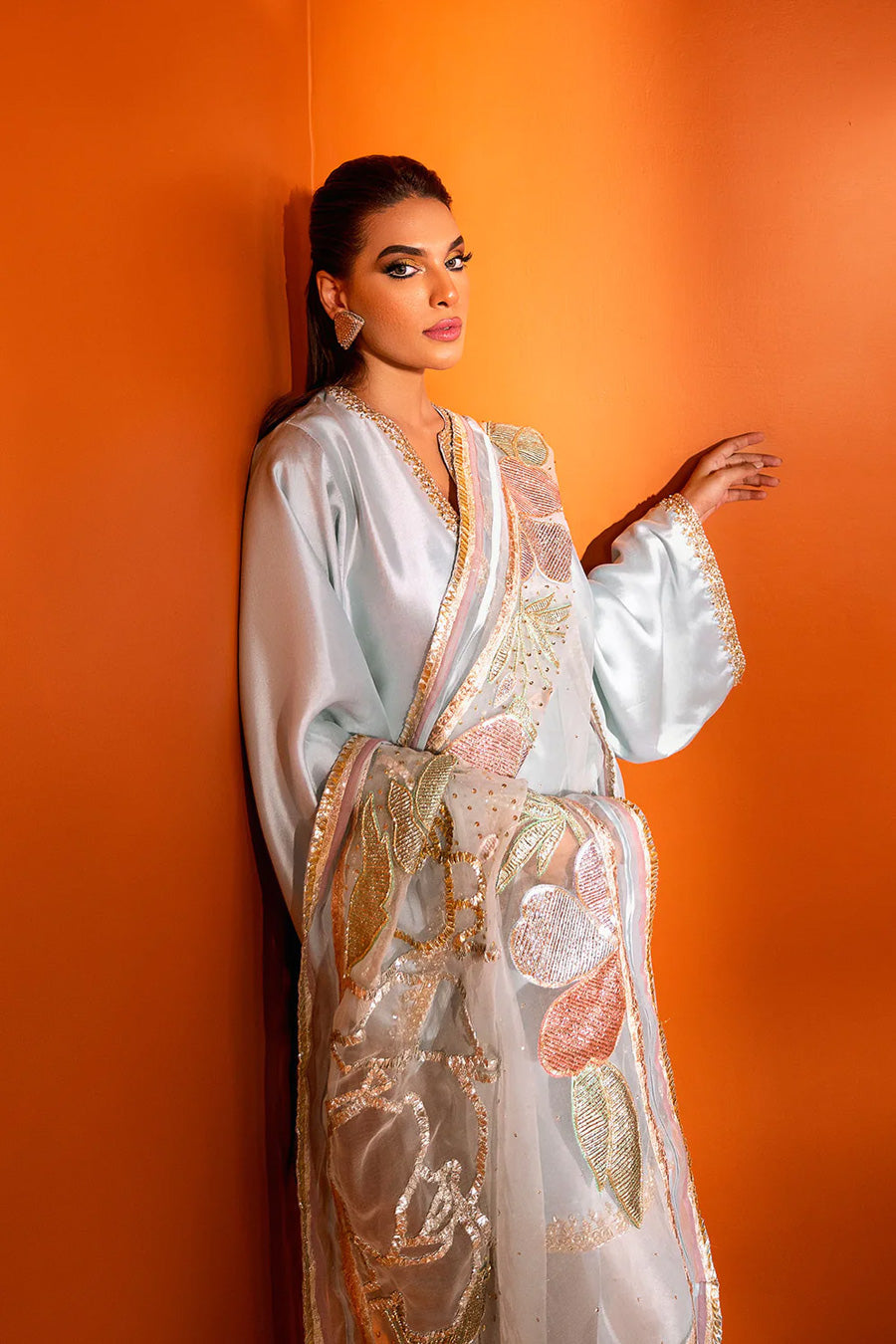 model in a closeup side shot wearing a formal light blue shalwar-kurta ensemble made in silk with the shalwar paired with an organza dupatta