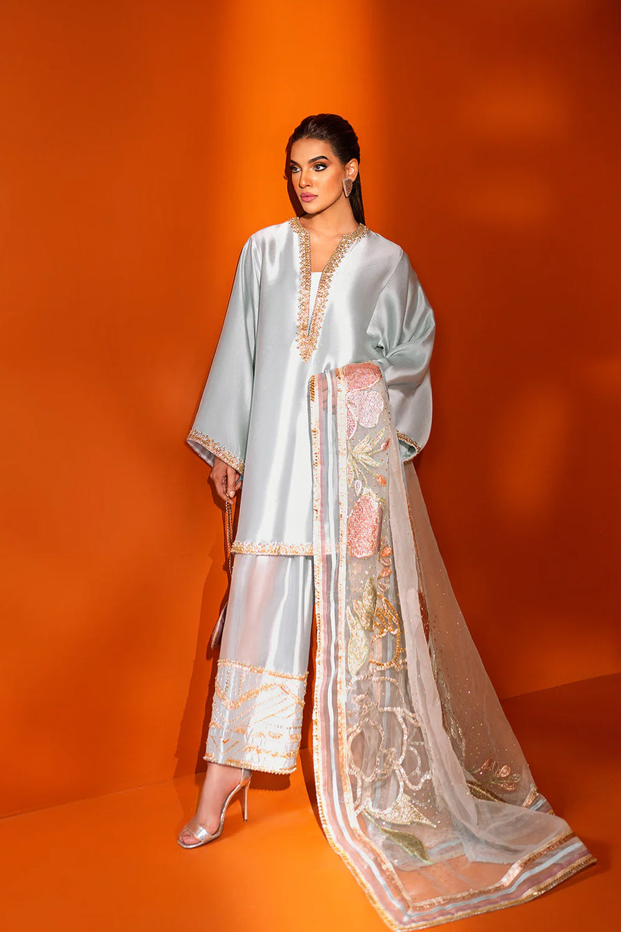 model in a front shot wearing a formal light blue shalwar-kurta ensemble made in silk with the shalwar paired with an organza dupatta