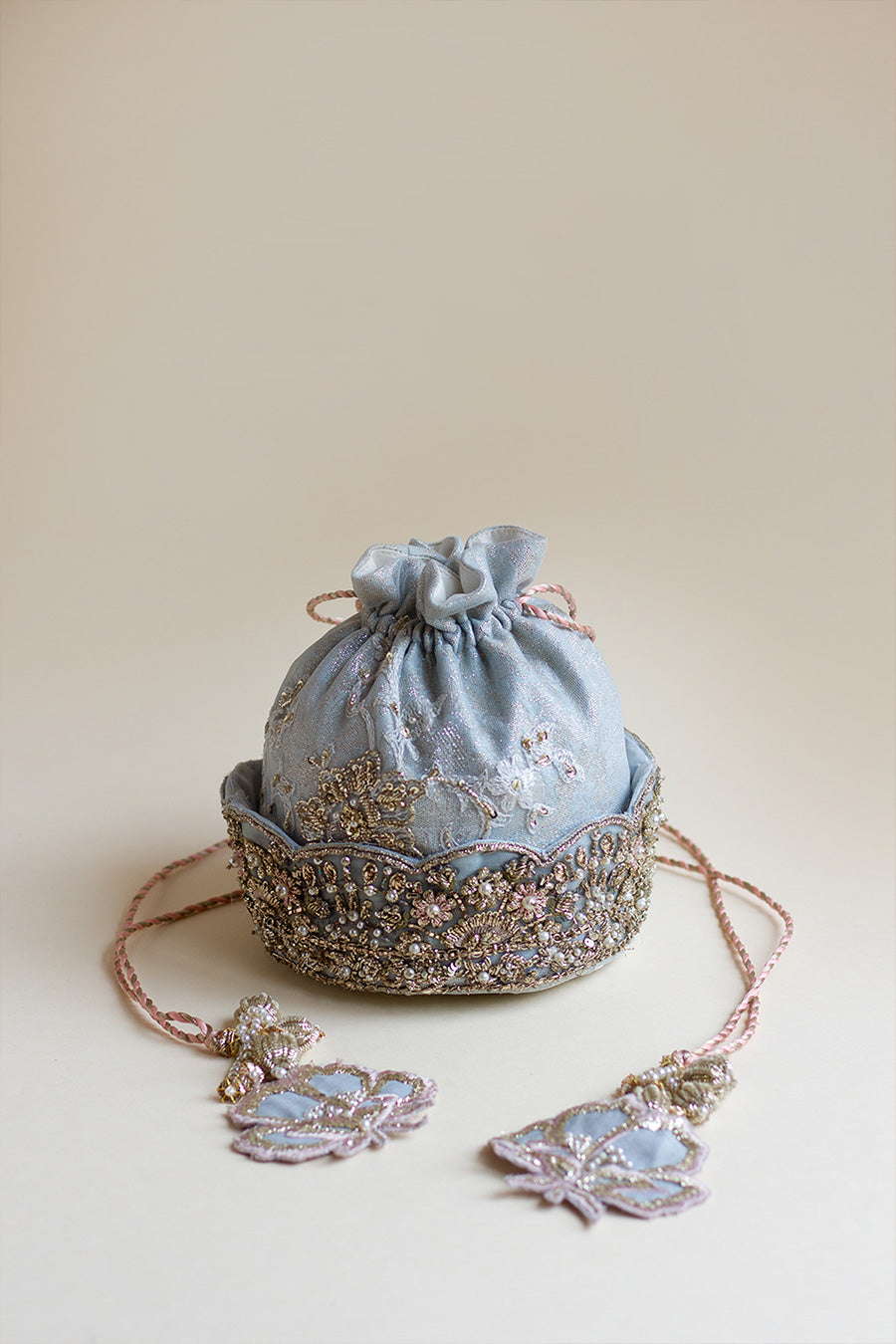 Full shot of light blue net dholki pouch with embroided flower and ball tassels