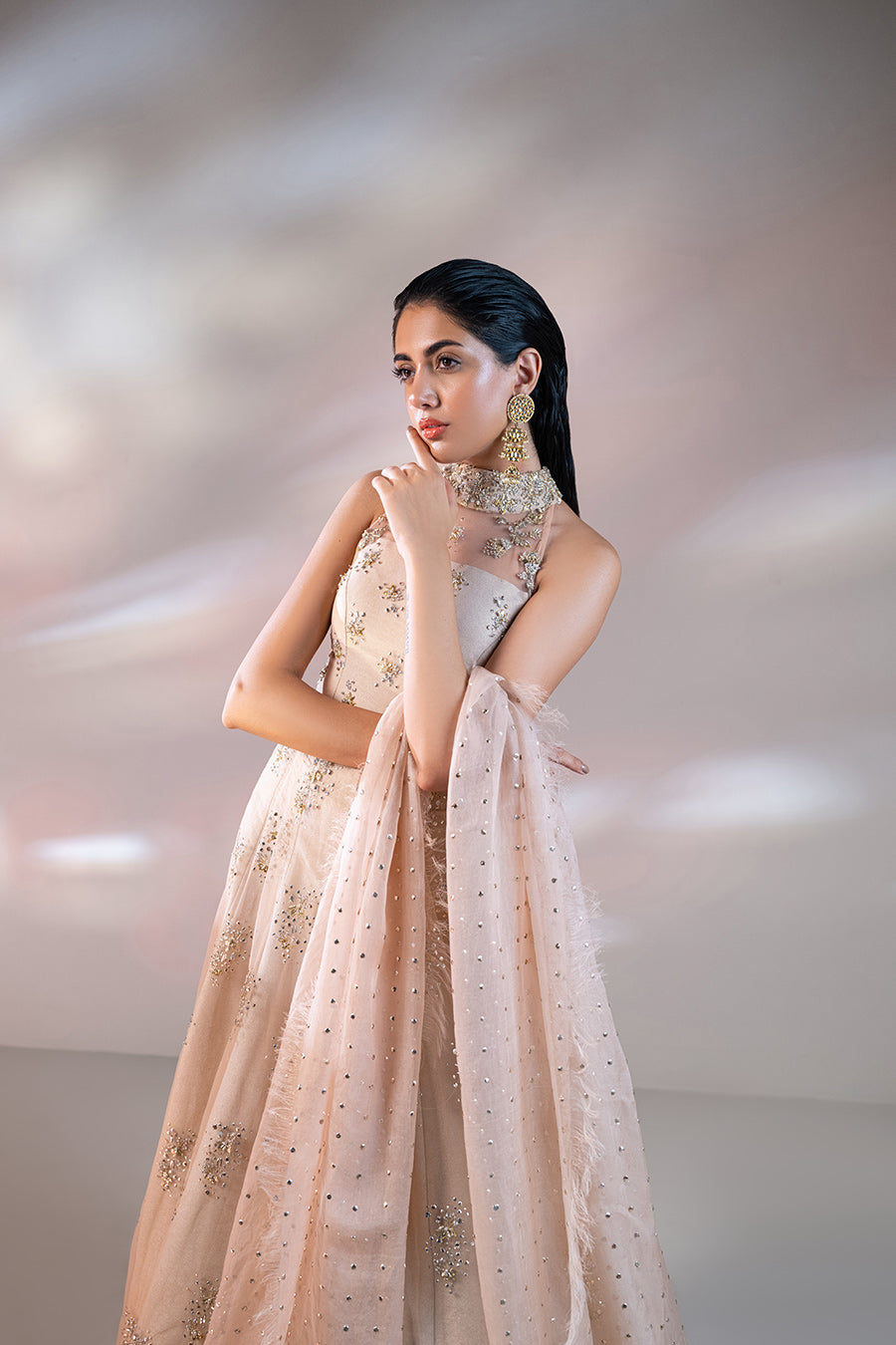 model in a closeup shot wearing a formal net mandarian collar with a front open slit shirt and paired with a shimmer light peach lehnga and a mokaish dupatta