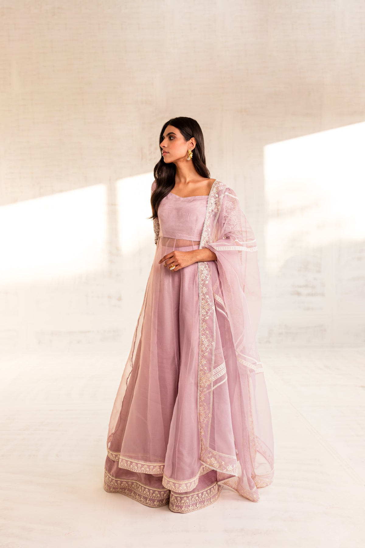 Model in a front view shot wearing an organza light pink long flared pishwas paired with an organza dupatta and silk katan trousers