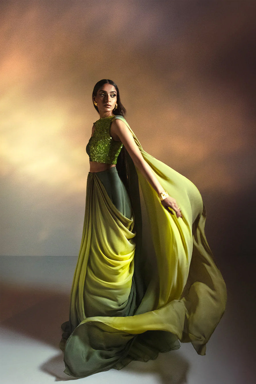 Model in a front shot wearing a lime green halter blouse paired with an ombre drape in Italian chiffon silk and a ruffled silk organza skirt