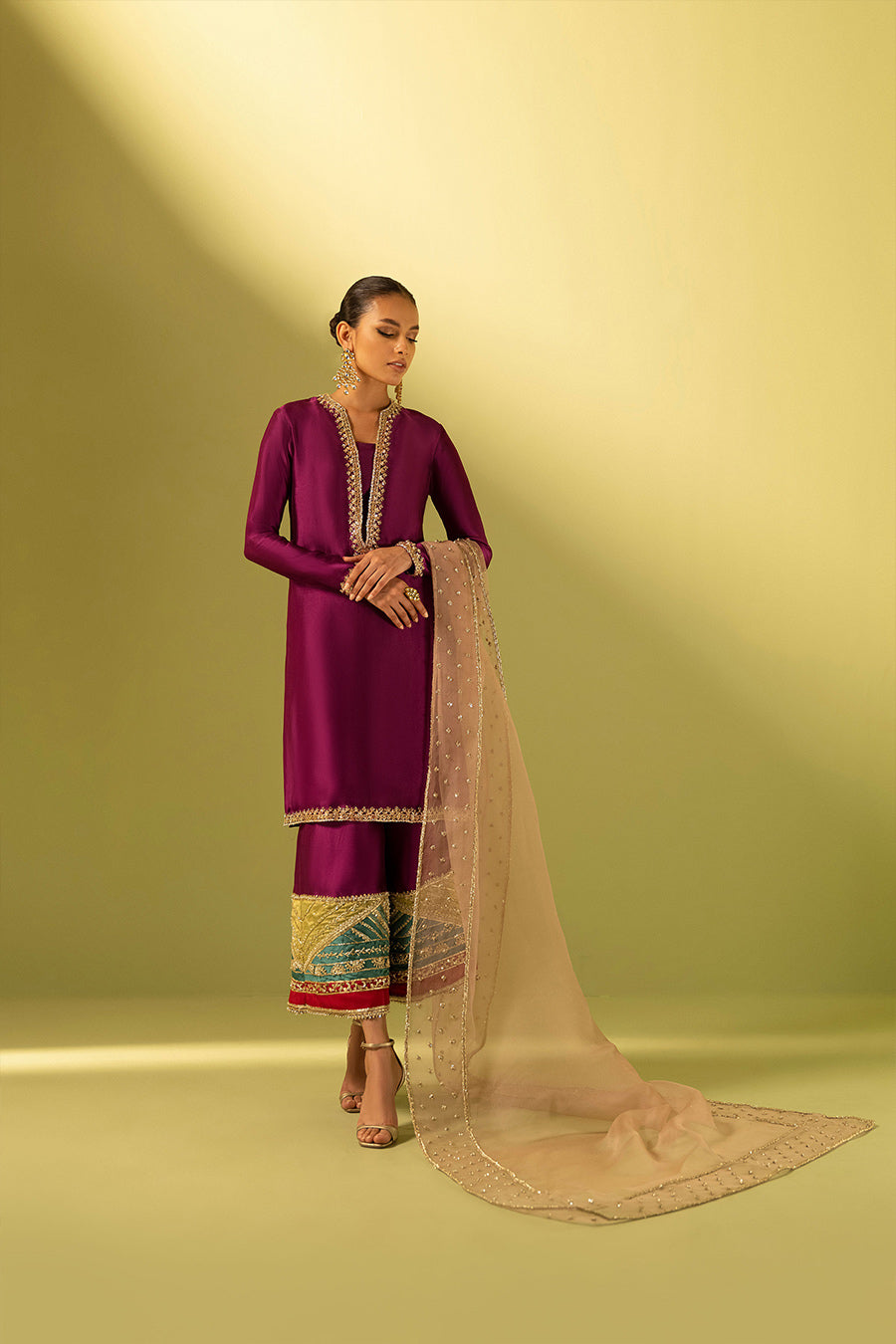 Model in a front shot wearing a magenta tissue raw silk culottes kurta paired with an embellished light pink organza dupatta