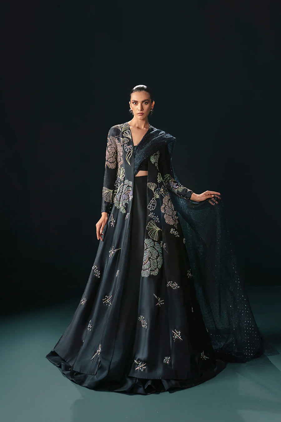 Model in a front shot wearing a midnight blue formal silk jacket paired with a bustier and skirt along with a drape attached to the lehenga