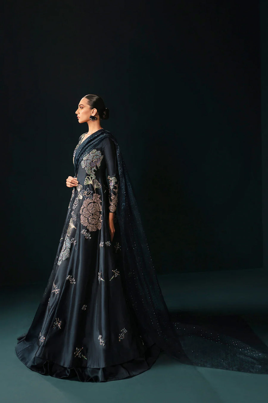 Model in side shot wearing a midnight blue formal silk jacket paired with a bustier and skirt along with a drape attached to the lehenga