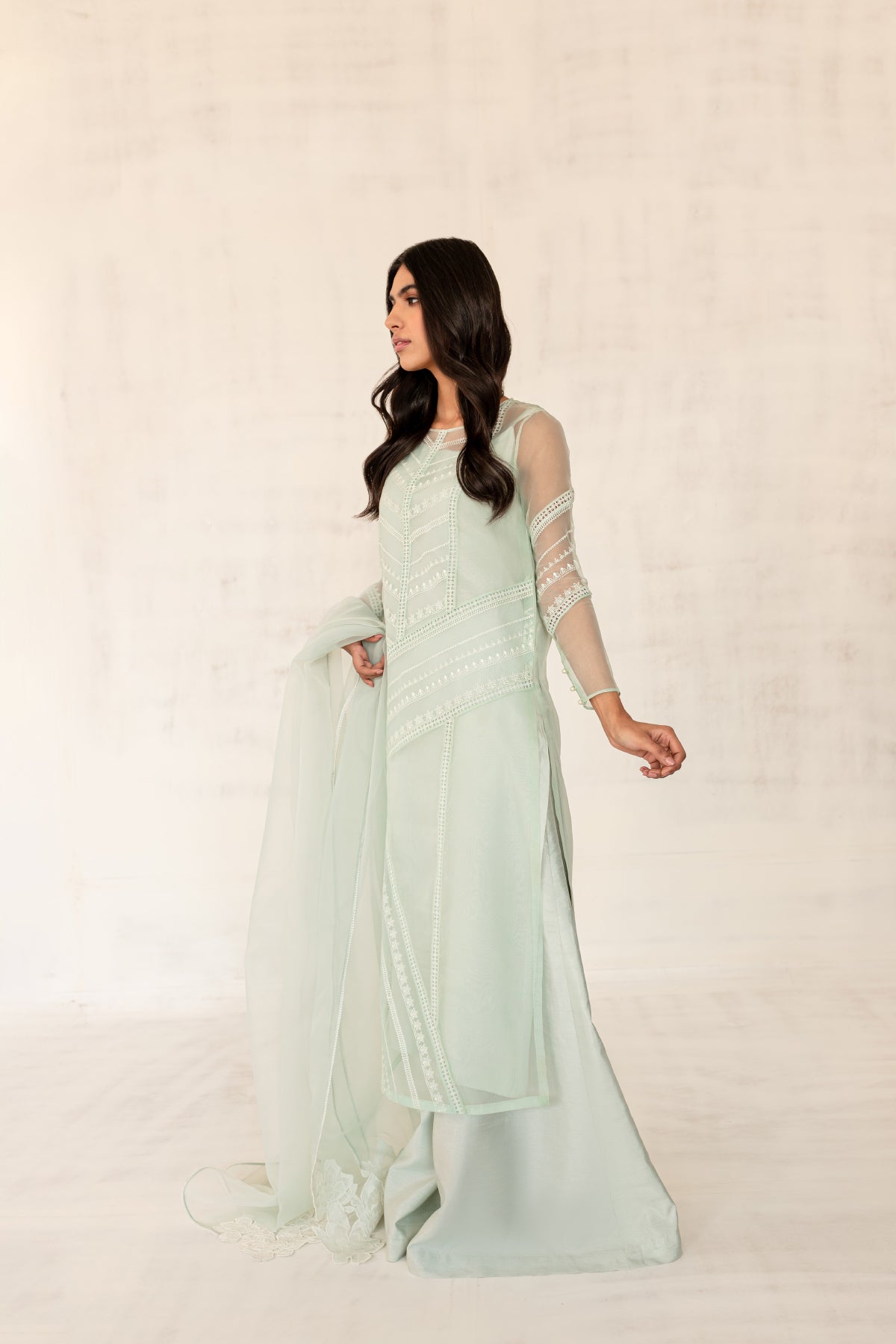 Model in a side view shot wearing a mint long organza shirt paired with an organza dupatta and silk katan pants