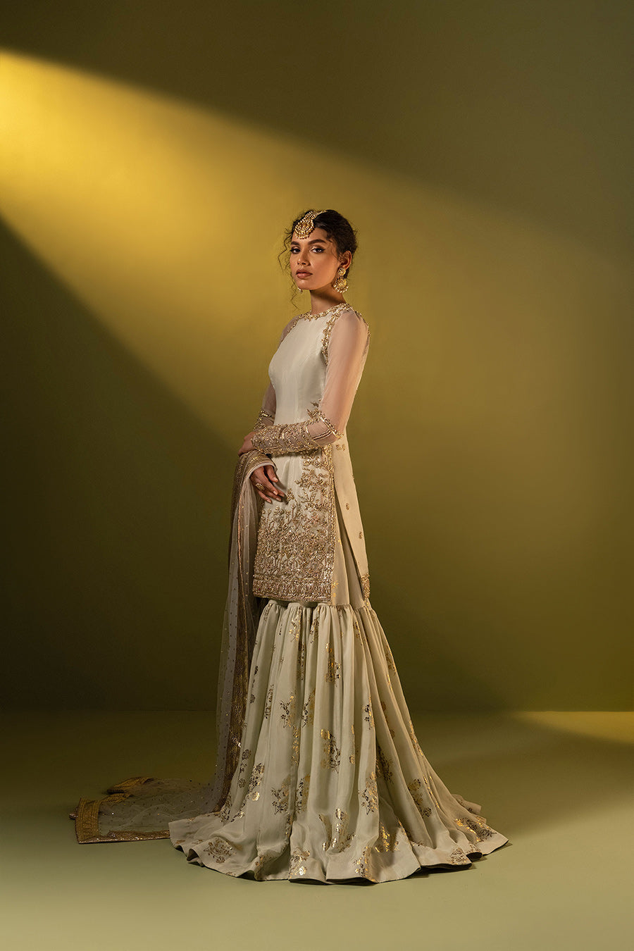 Model in a side shot wearing formal pistachio organza shirt paired with a silk chiffon gharara and a net dupatta 