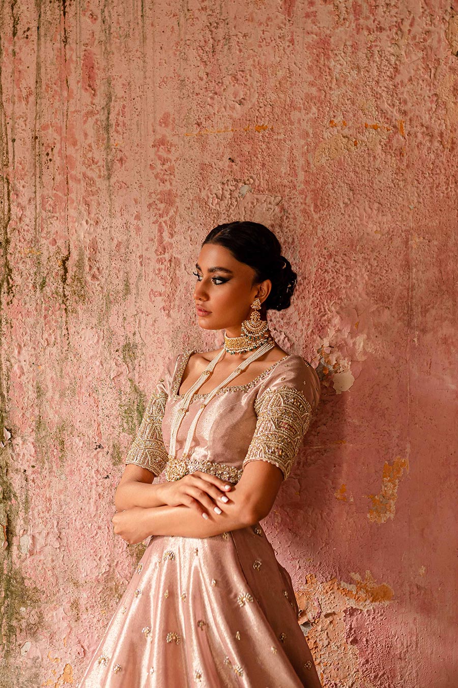 Model wearing a plum purple bridal lehenga dress with floral border and motif detailing with thread work, zardozi, sequin, and pearl detailing