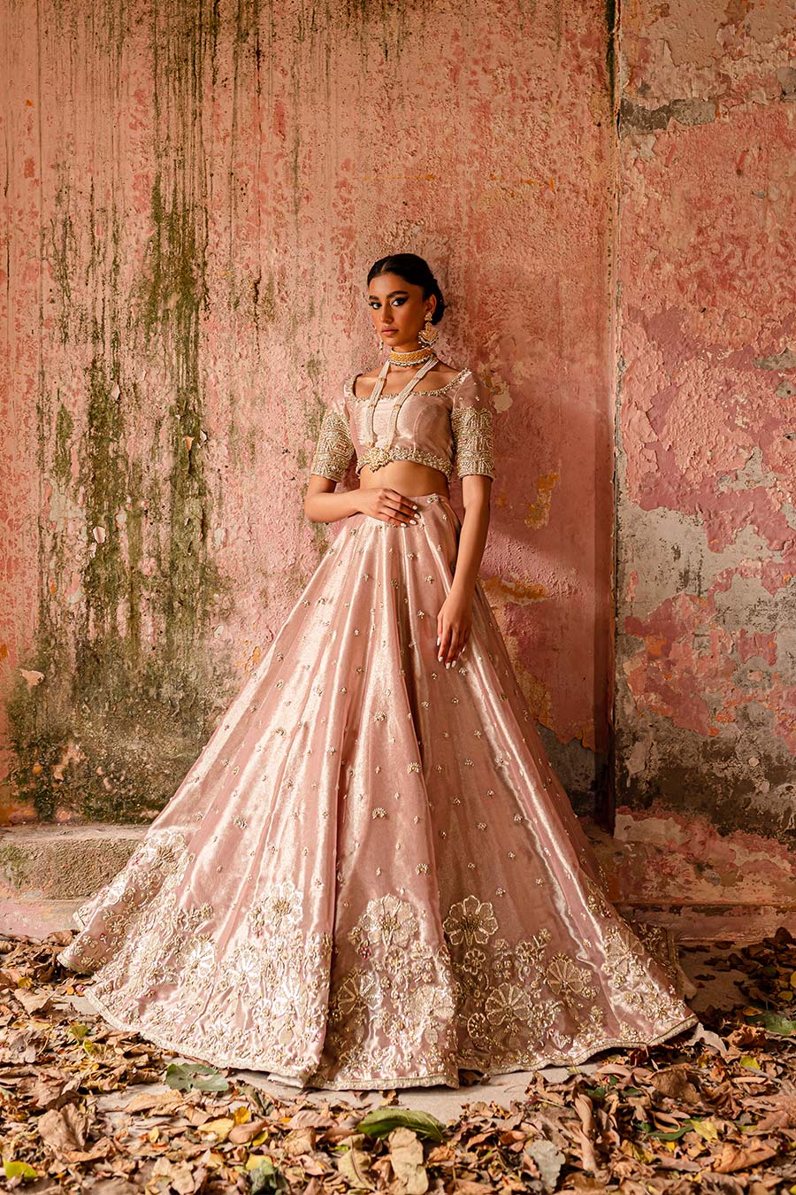 Model wearing a plum purple bridal lehenga dress with floral border and motif detailing with thread work, zardozi, sequin, and pearl detailing