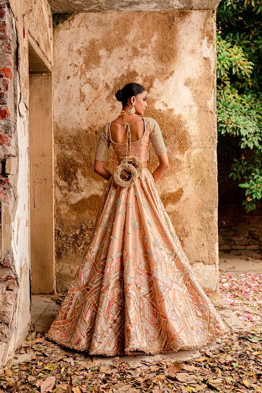 Model wearing a warm peach bridal lehenga dress with thread work, zardozi, and sequin embellishments with pastle pink dupatta by Zuria Dor