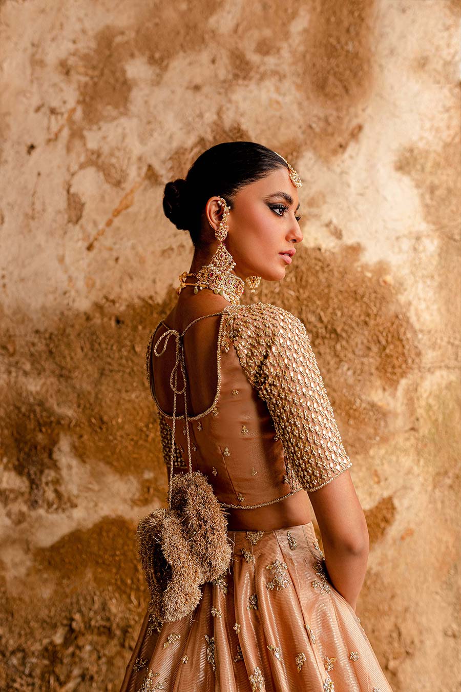 Model wearing a warm peach bridal lehenga dress with thread work, zardozi, and sequin embellishments with pastle pink dupatta by Zuria Dor