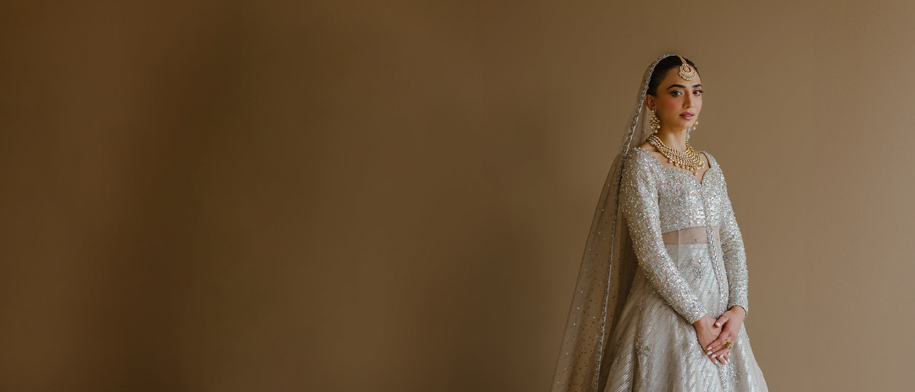 Model wearing silver peshwas paired with a metallic lehenga completed with a Zari net dupatta