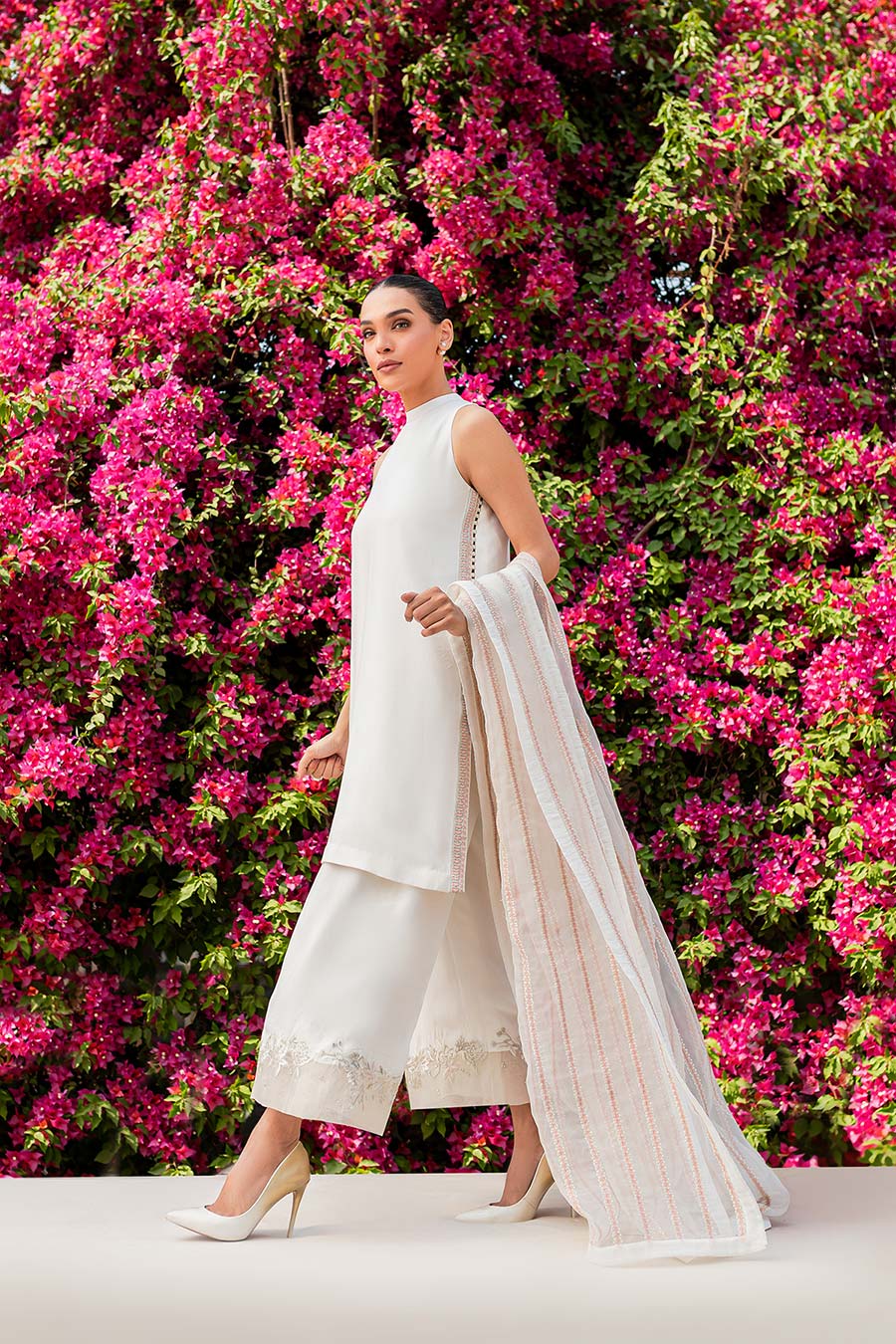 model in a side shot wearing matte silk halter shirt paired with trousers and organza dupatta 